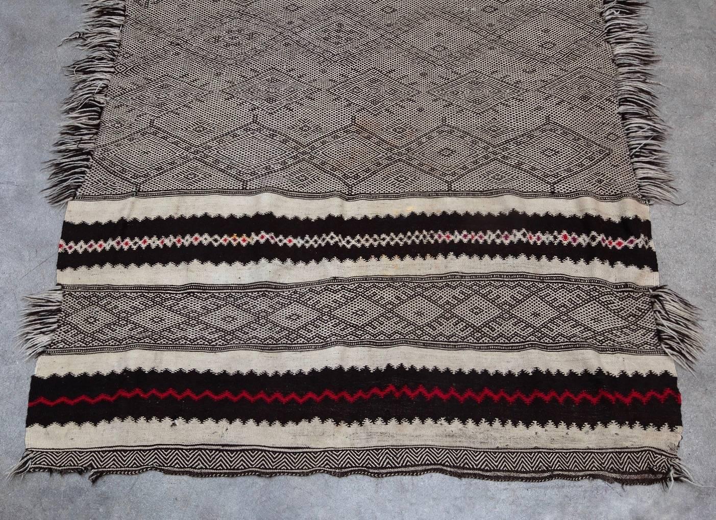 This piece is a rare and older style type of Zanafi rug. Hand woven by Berber tribes who reside in the high Atlas Mountains in Morocco. Zanafi rugs are known by the special pattern which consist of different elements of zigzags, triangles, diamond