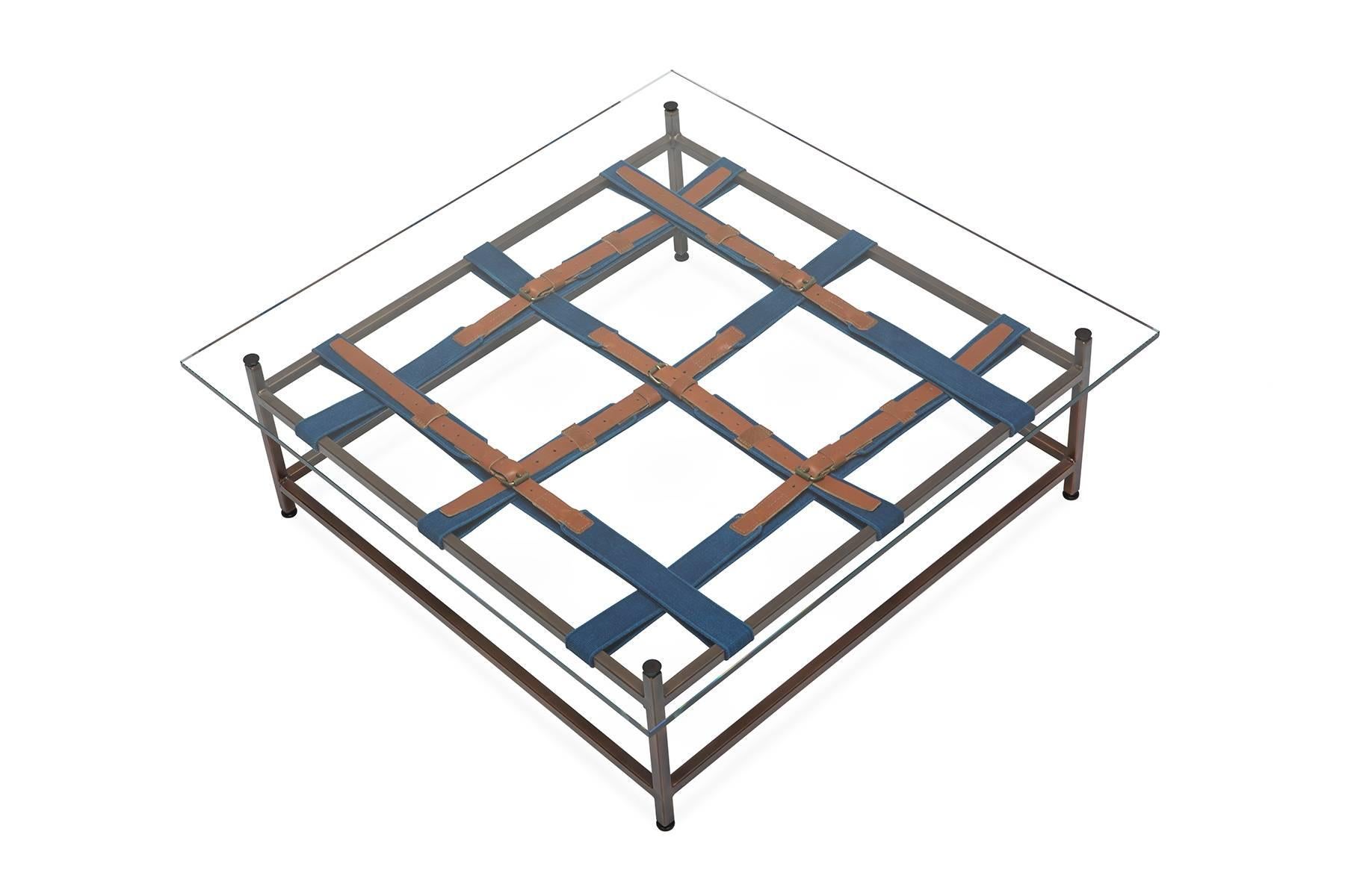 A glass topped coffee table that utilizes the signature Inheritance collection belts. This version was made to pair with the hand-dyed indigo canvas and antique copper sofa. The steel frame has an antique copper finish and naturally dyed indigo