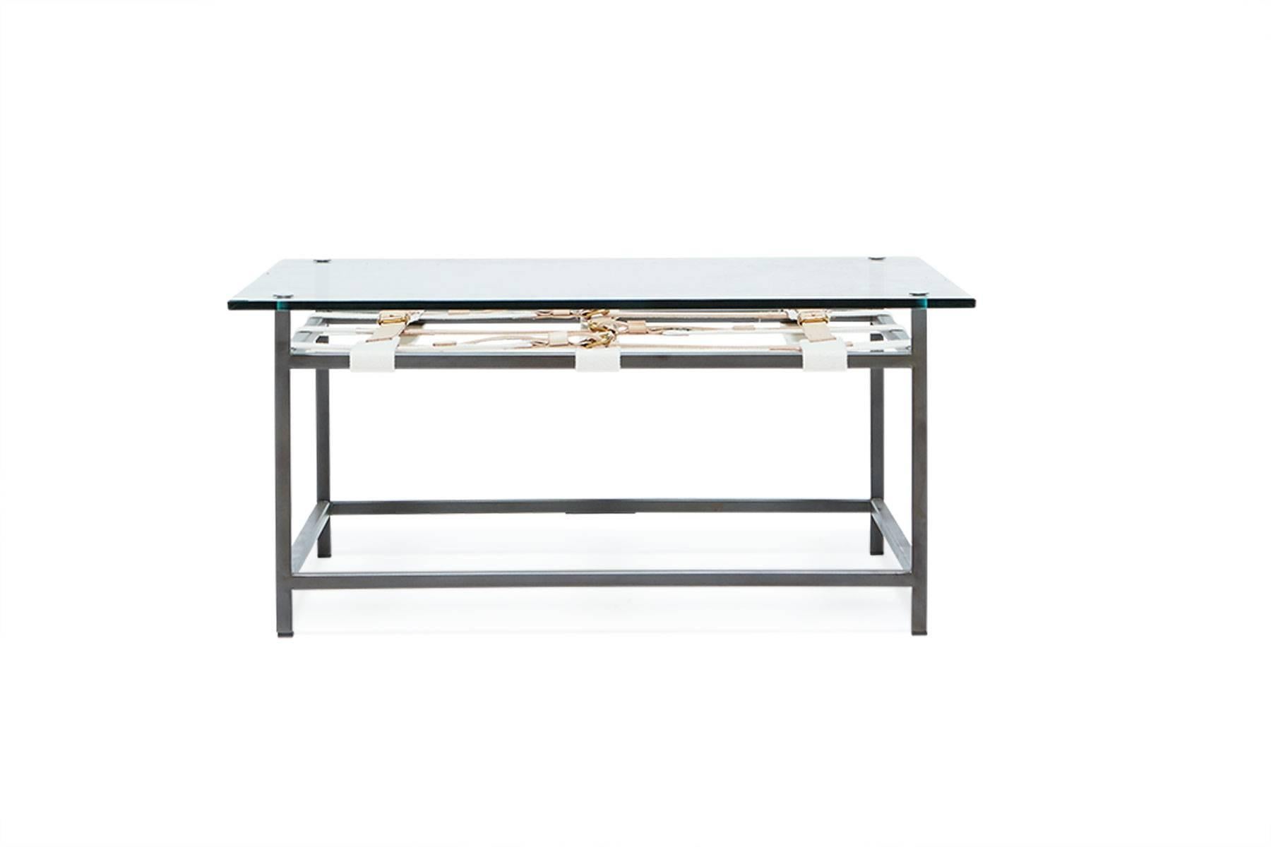 A glass topped coffee table that utilizes the signature Inheritance collection belts. The steel frame has a blackened steel finish and natural cotton webbing belts with natural veg tanned leather and polished brass buckles.

This item is made to