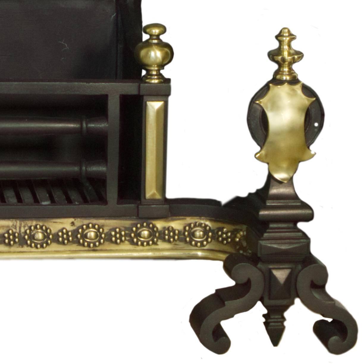 An exceptional rare large English 18th century cast iron and polished brass fire basket. With a decorative high fire-back, detailed brass fret work to the apron, unique emblem applied to the fire dogs with solid brass finials. Salvaged from a
