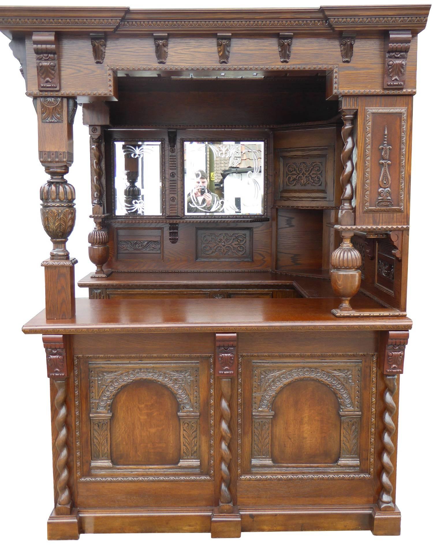 For sale is a good quality, carved oak corner bar. The bar has an inverted breakfront canopy, decorated with carved corbels and a stained glass ceiling. This is supported by the two back sections, each with beveled and hand engraved mirrors, as well