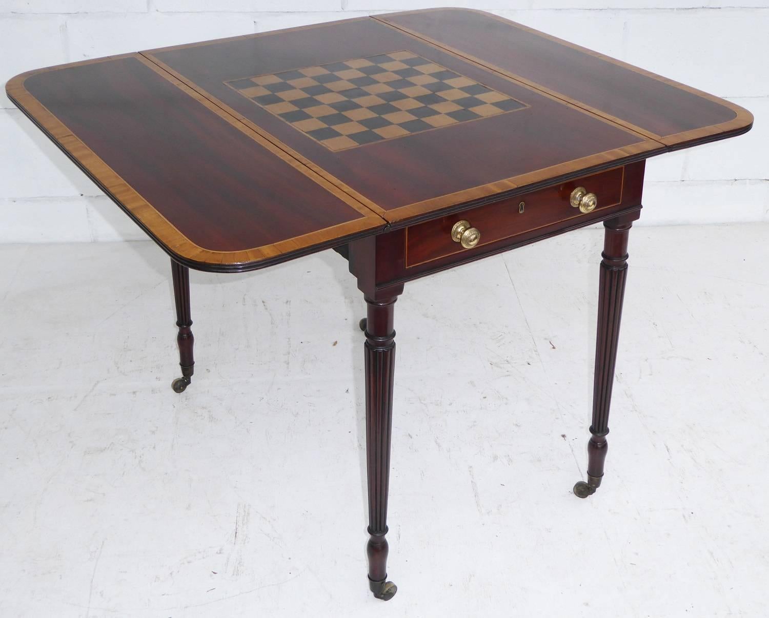 For sale is a good quality William IV mahogany and satinwood pembroke table with a games top. The centre of the table has a chess board, surrounded by satinwood inlay and satinwood banding to the edge. On either side of the table is a lift up flap,