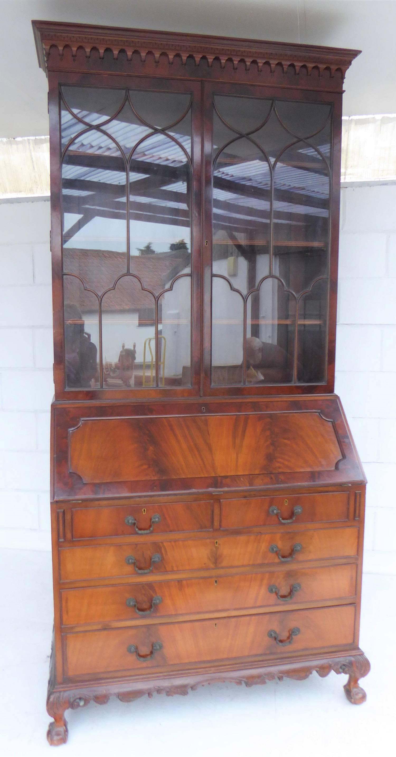 
Good quality Mahogany Chippendale style Bureau bookcase in nice condition. The upper section has a pendant moulded dentil cornice with three adjustable shelves enclosed by two astragal glazed doors. The sloping fall enclosing fitted interior with