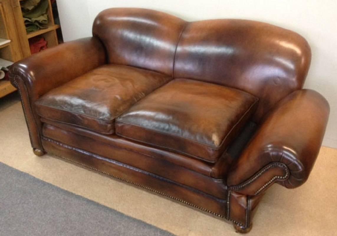 For sale is a very good quality antique, hand dyed conker brown leather, two-seat drop end sofa with feather stuffed cushions. The sofa has elegant scroll arms and stand on walnut bun feet terminating on brass castors, also with an unusual drop end
