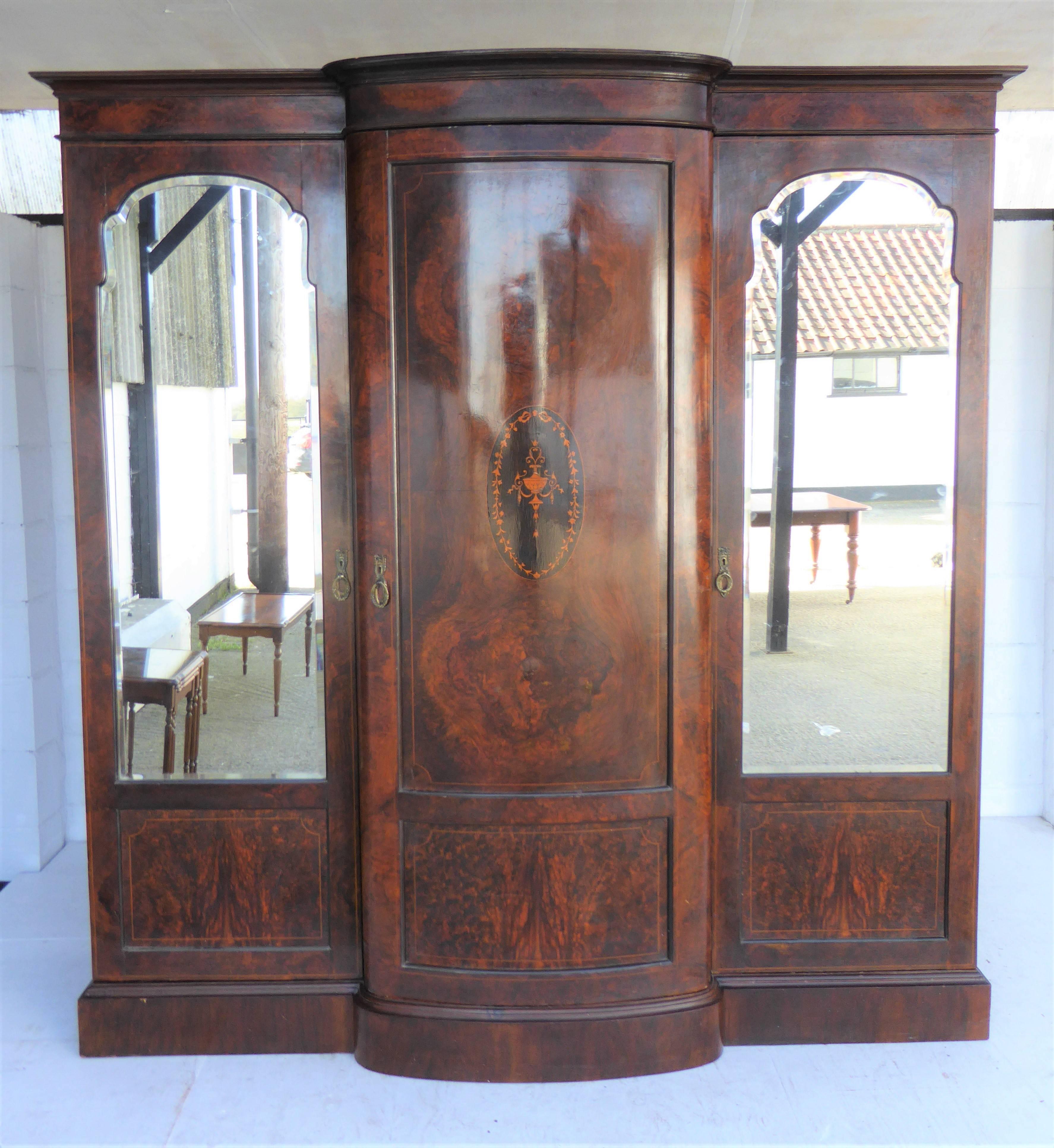 Late Victorian Burr Walnut Inlaid Triple door Wardrobe linen press compactum in original condition. Raised on a plinth base with central Inlaid bowfronted door flanked by bevelled mirror doors.The right and  left hand side encloses shelf over