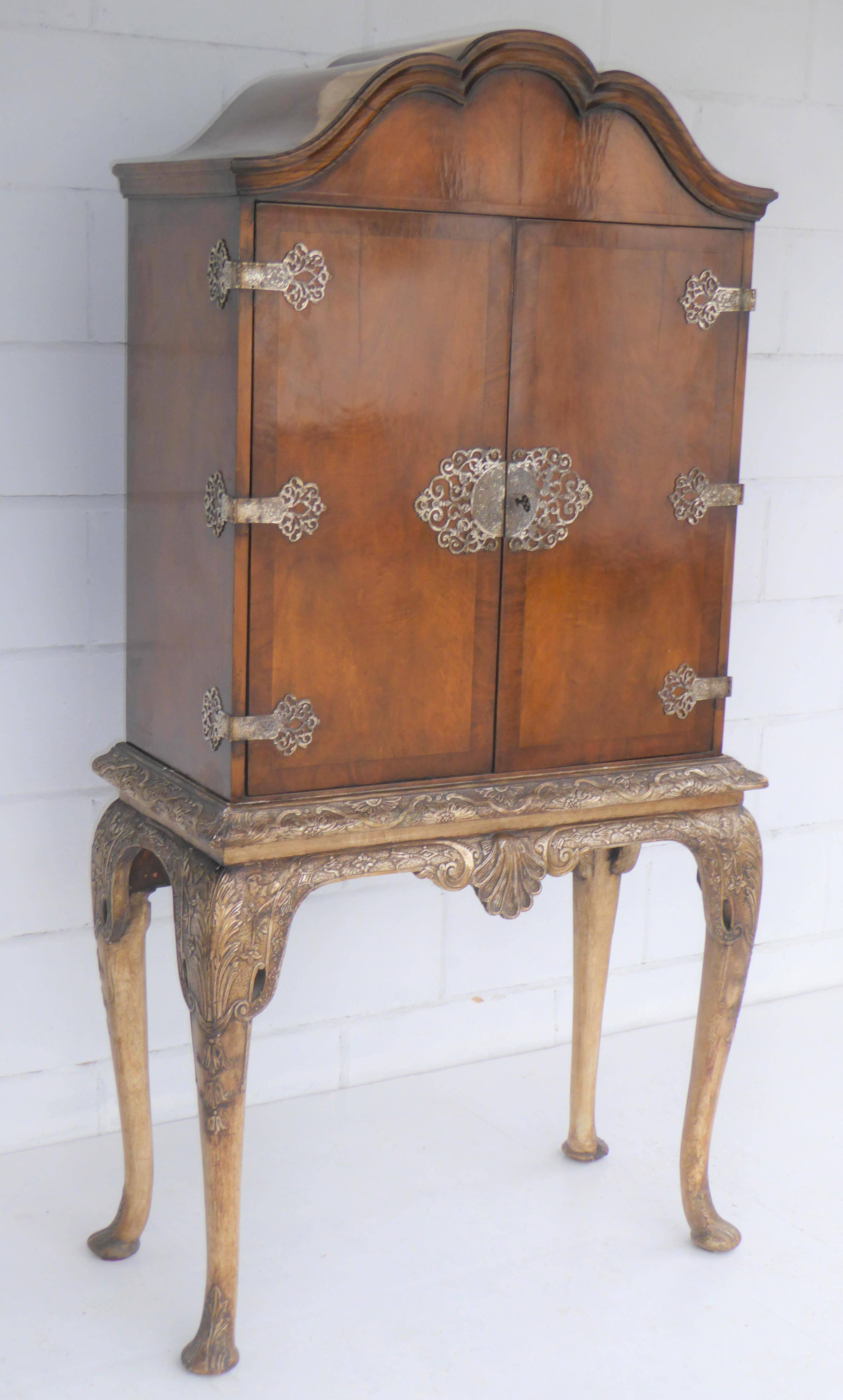 Queen Anne figured walnut cocktail cabinet on silver gilt stand in nice condition having two cupboard doors, when opened reveals a mirrored interior with two glass shelves and glass pull out slide, stands on silver gilt stand with cabriol legs.