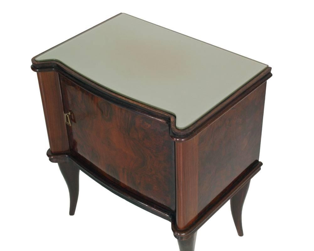 
Mid-Century pair nightstands 1950s Vittorio Dassi manner in folder and burl walnut, legs in dark beech, walnut burl flame veneer on the doors and sides; interior in mahogany folder. Glass top, and handles in gilt brass.

Measure cm: H 58, W 52, D