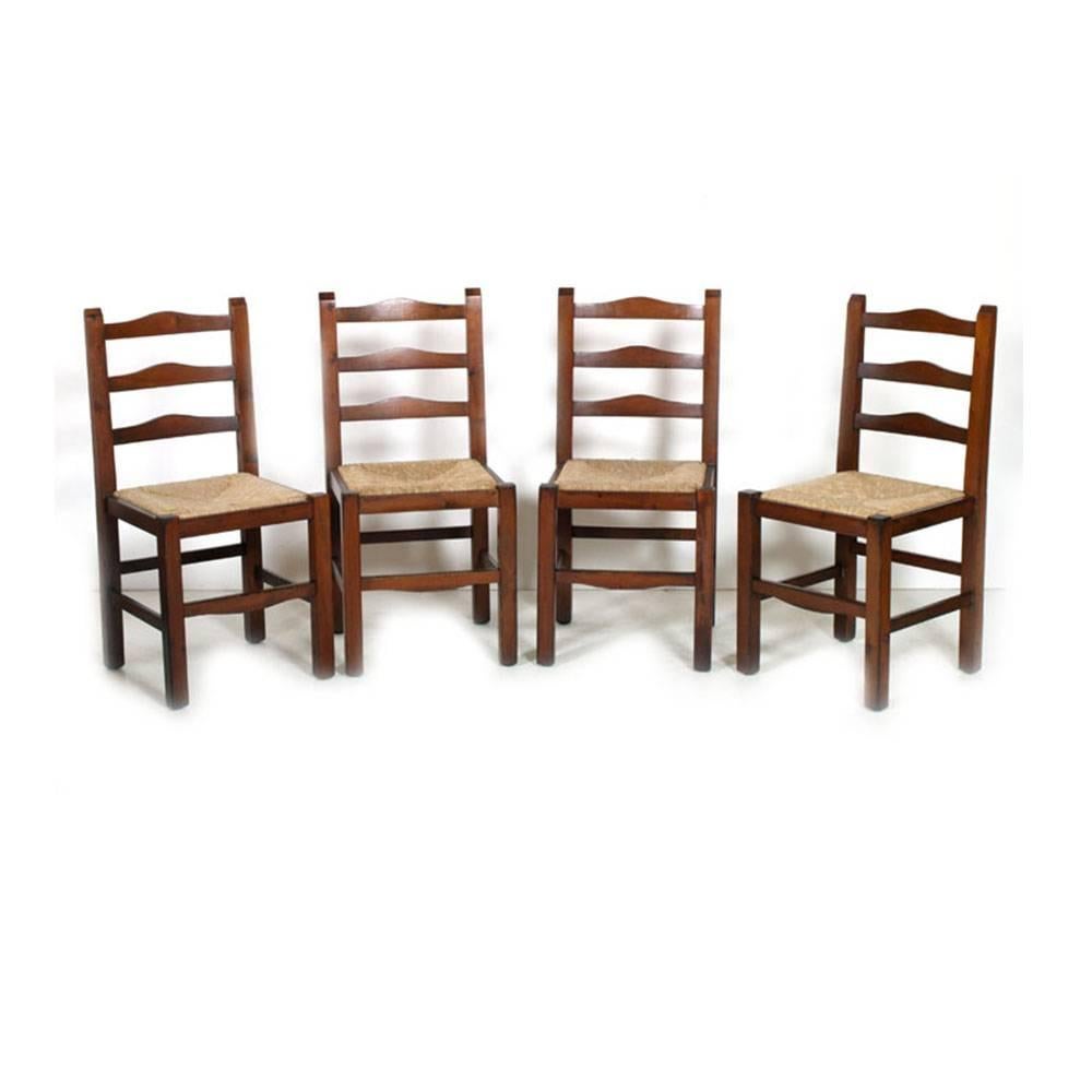 Set four Mid-Century Modern sturdy country rustic chairs in chestnut wood, polished to wax, sitting in straw.