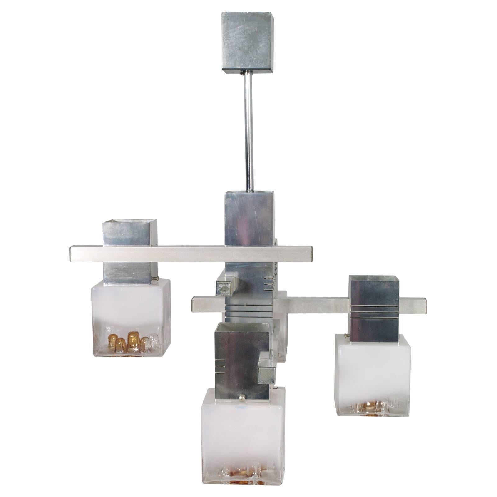 Charmant lustre des années 1970 avec structure en aluminium et cinq lampes cubiques en verre de Murano par Mazzega.
Système électrique refait, prêt à l'emploi.

Dimensions en cm : D 60, L 60, H 77.