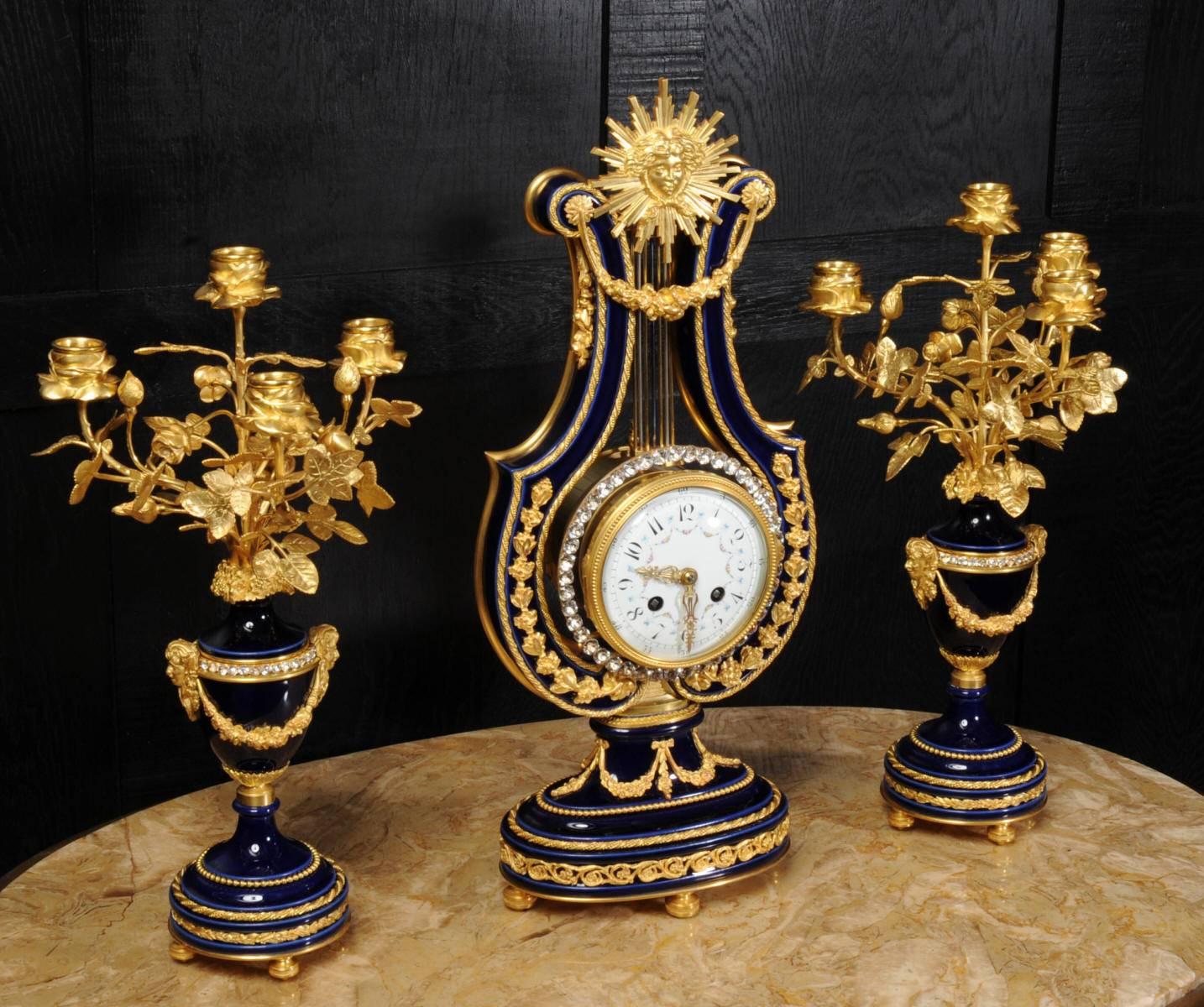 Antique French clockset, one of the nicest Louis XVI designs, elegant lyre shape in cobalt blue Sevres style porcelain mounted with exquisite ormolu (finely gilded bronze doré).
A paste jewel set bezel surrounding the clock forms the mystery