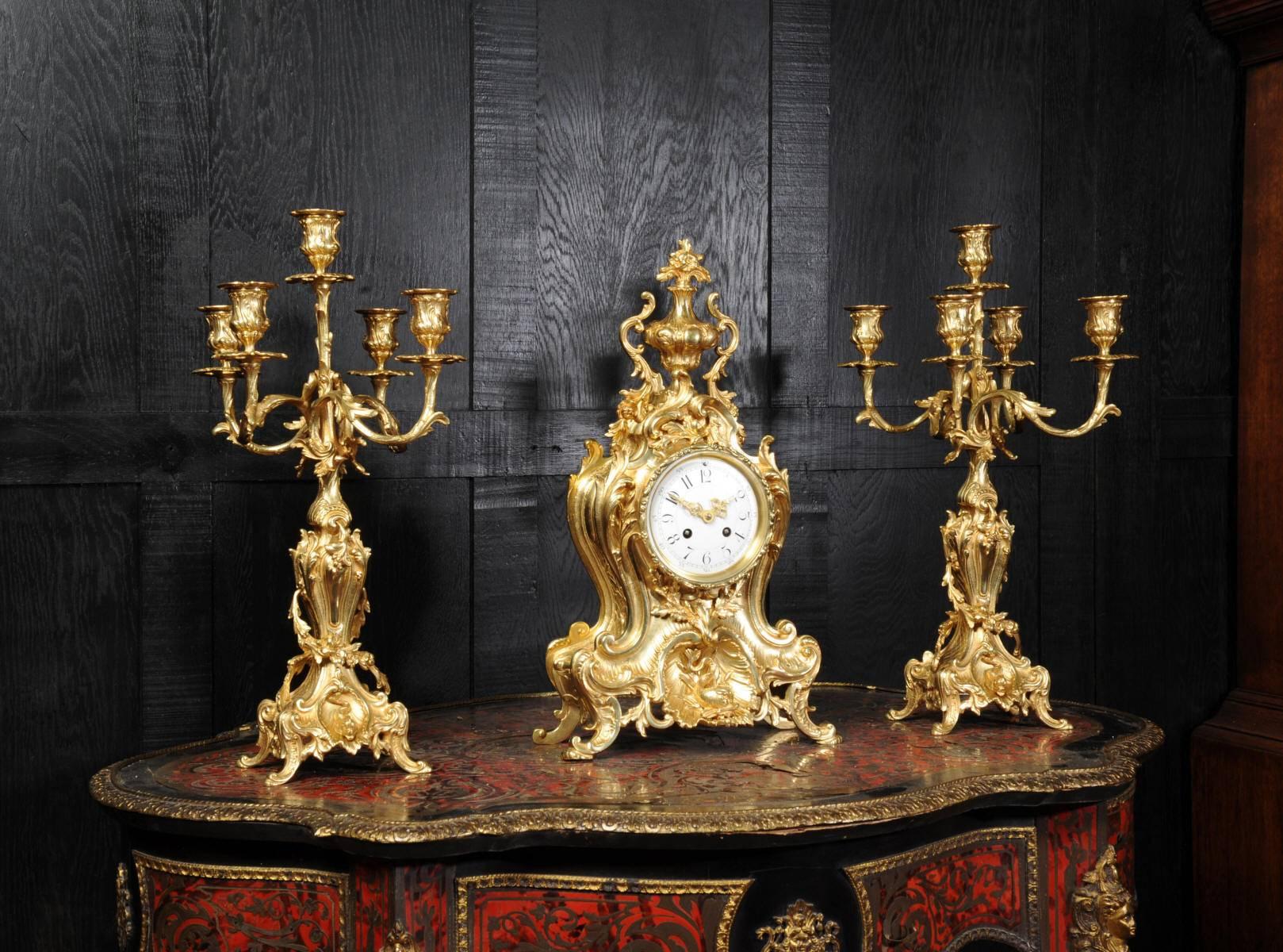 A stunning and large original antique French ormolu (gilded bronze) clock set, circa 1880, featuring dolphins. It is of the most beautiful Rococo style, asymmetric waisted case decorated with 'C' scrolls, acanthus leaves and floral swags. To the top