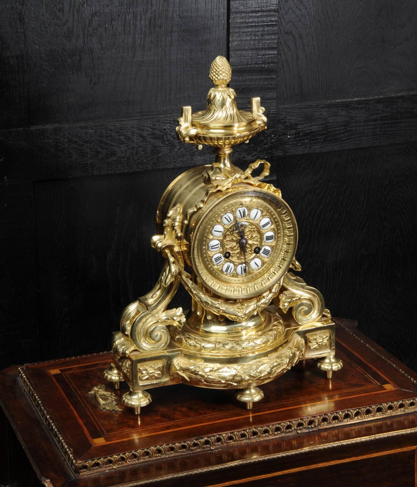 A stunning original antique French clock of neoclassical design in gilded bronze. It is in excellent condition, the movement fully overhauled. The movement is mounted in a drum on top of a reeded column. Scroll supports are to the sides and a laurel