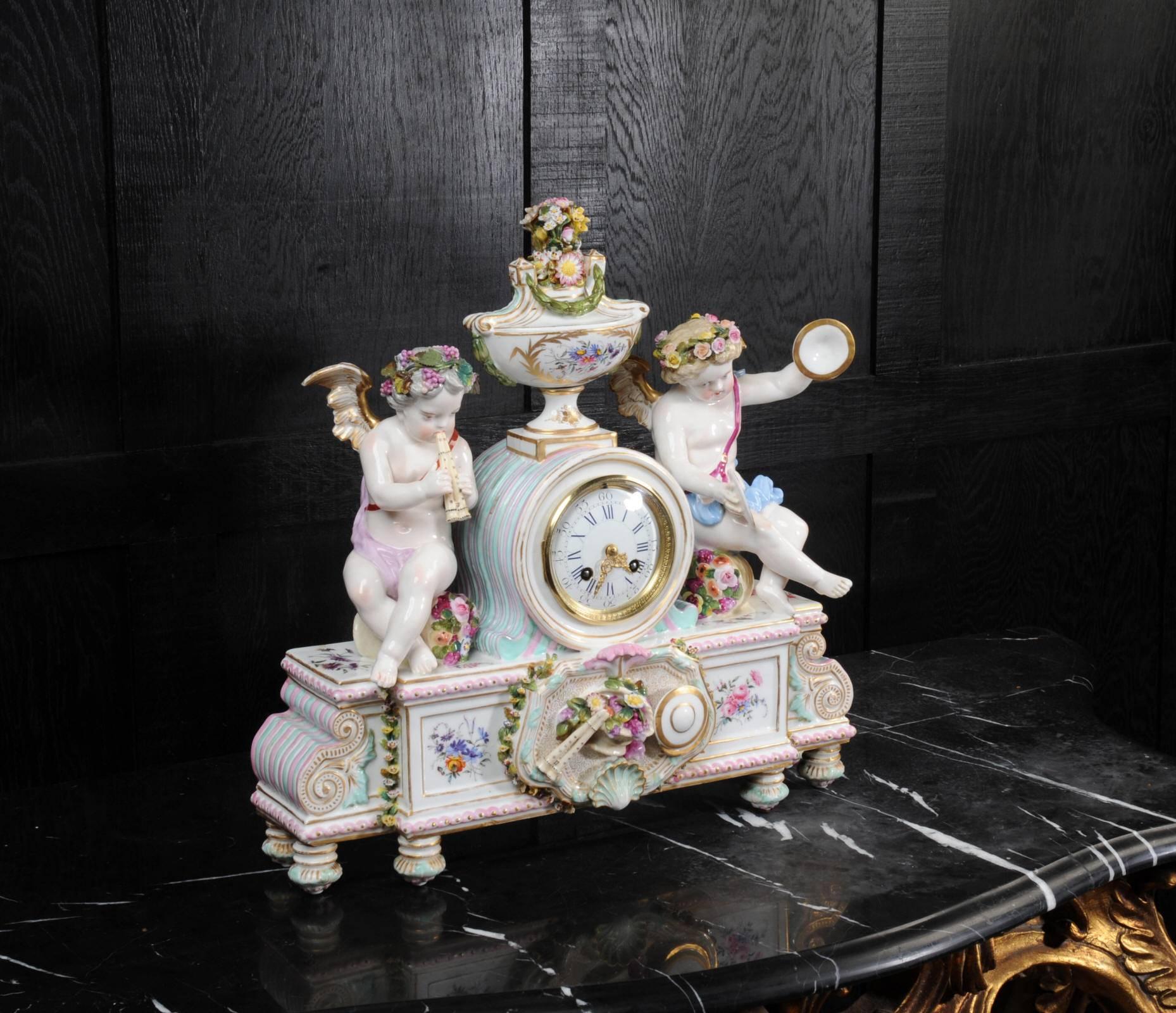 A large and beautiful antique French clock of exquisite Meissen style porcelain in the Louis XV style. Porcelain is profusely applied with delicate flowers. It features two putti with musical instruments, one with double flute and the other playing