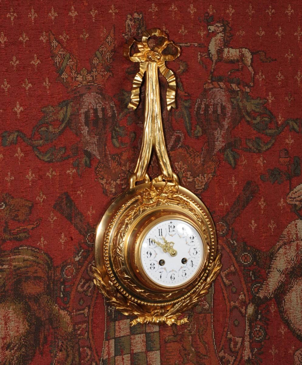 A very delicate and decorative original antique French cartel wall clock. It is in the style of Louis XVI with the movement mounted in a round case supported from a bow. The case is adorned with a bow and swags of acanthus, all beautifully made in