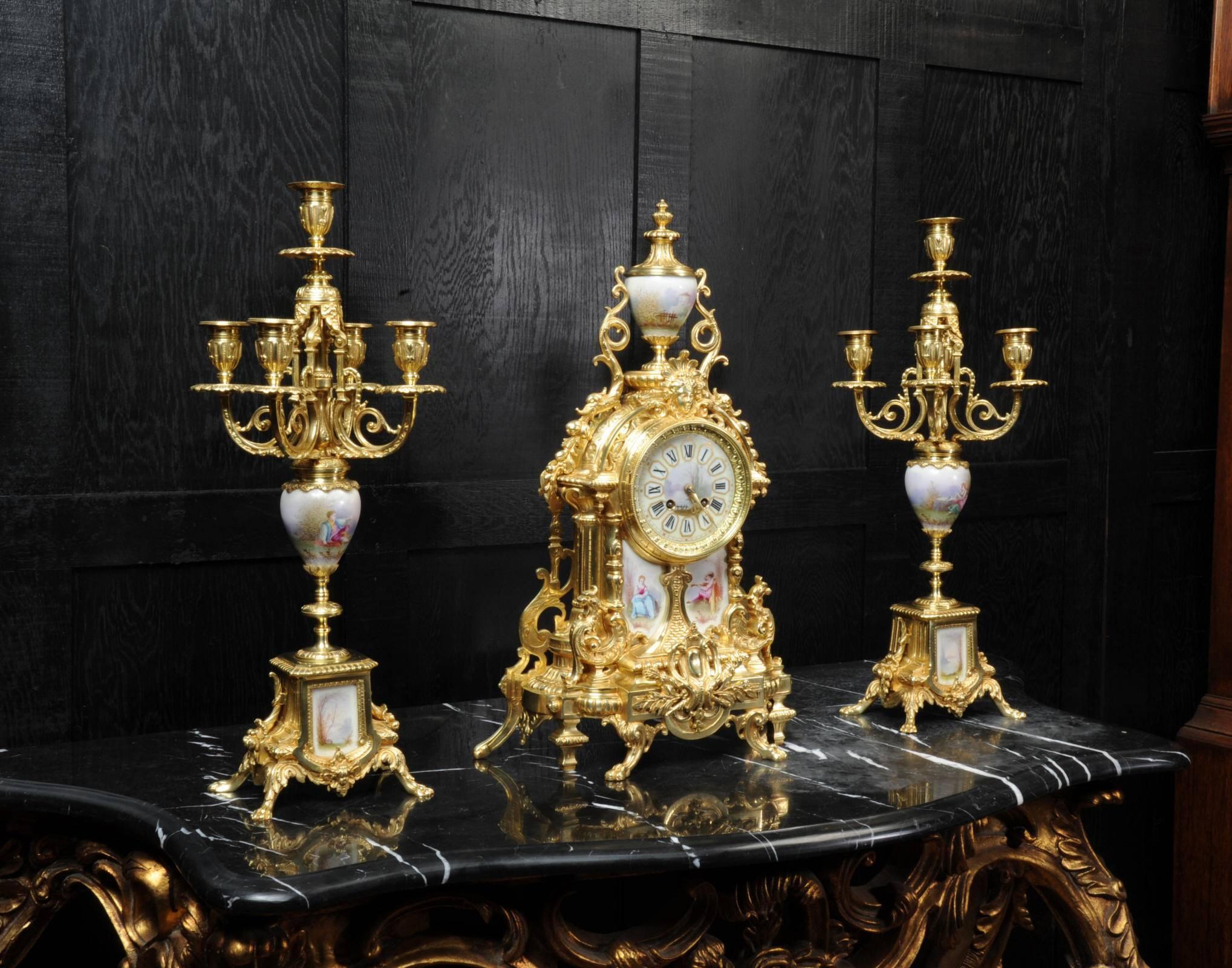 A large and stunning ormolu and Sèvres style porcelain clock set, in lovely fully overhauled condition. The original finely gilded bronze is in excellent condition with exquisitely painted porcelain panels and urns featuring a young couple in a