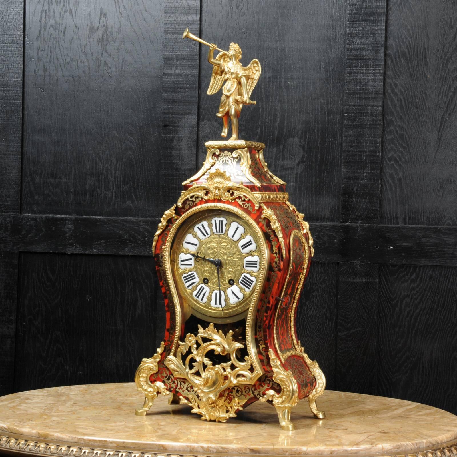 A stunning original antique French Rococo clock standing over 2 feet in height. Sumptuously made Boulle marquetry of red shell veneer delicately inlaid with brass and mounted with fine ormolu (fine gilded bronze). Beautiful Rococo shape with glazed