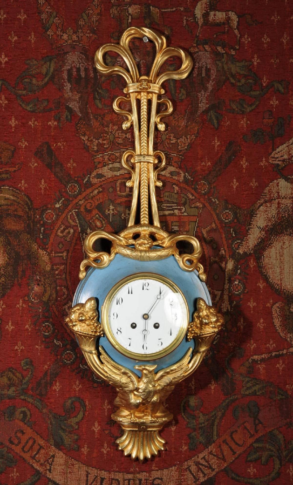 A large, unusual and very decorative original French antique Cartel wall clock. It is classical in design, hanging from a large gilt bronze bow with a laurel wreath. The clock is mounted in a toleware body with original blue painted finish. Below