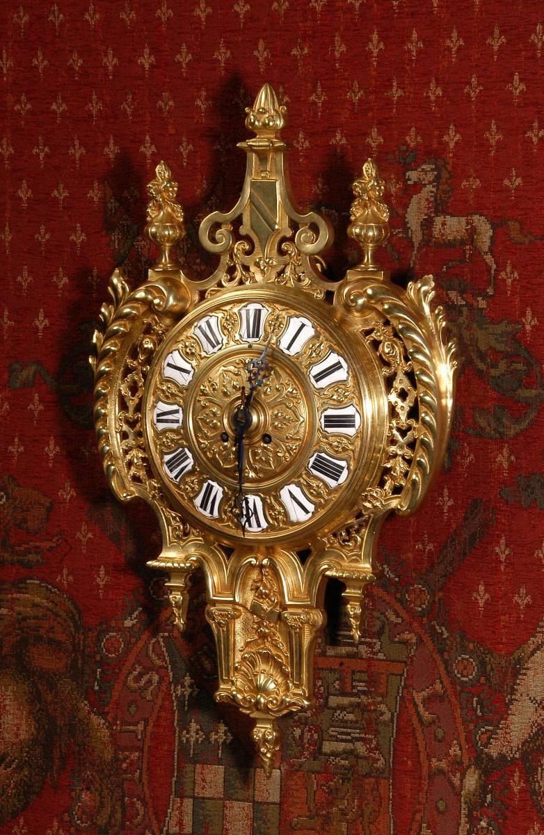 Une superbe horloge murale Cartel de style baroque, ancienne et française. Il est magnifiquement modelé en bronze doré en forme de bouclier. Les côtés sont ornés de rinceaux d'acanthe et de panneaux finement ajourés, tandis que le haut est orné d'un