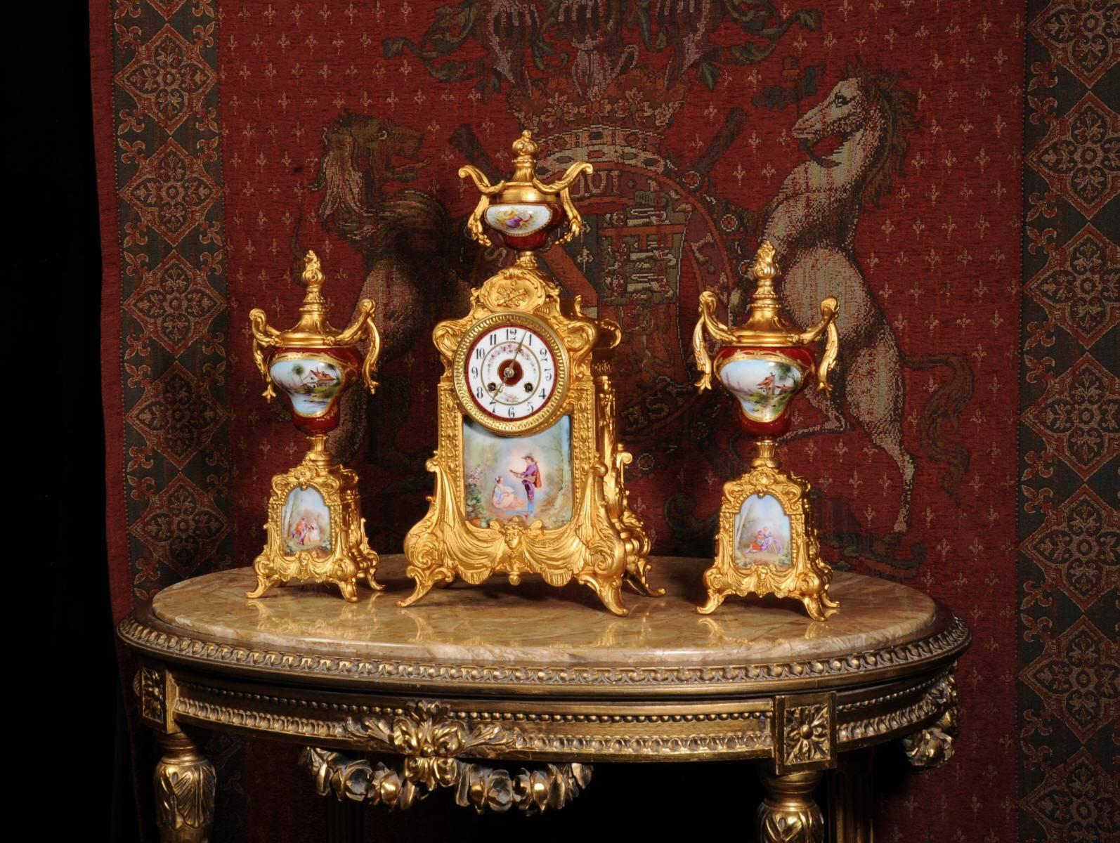 A large and very decorative gilt metal clock set mounted with exquisitely painted Sèvres style porcelain urns and panels. The panels show scenes of a young couple in a country setting, in one he plays the lute to her, in another they drink wine and