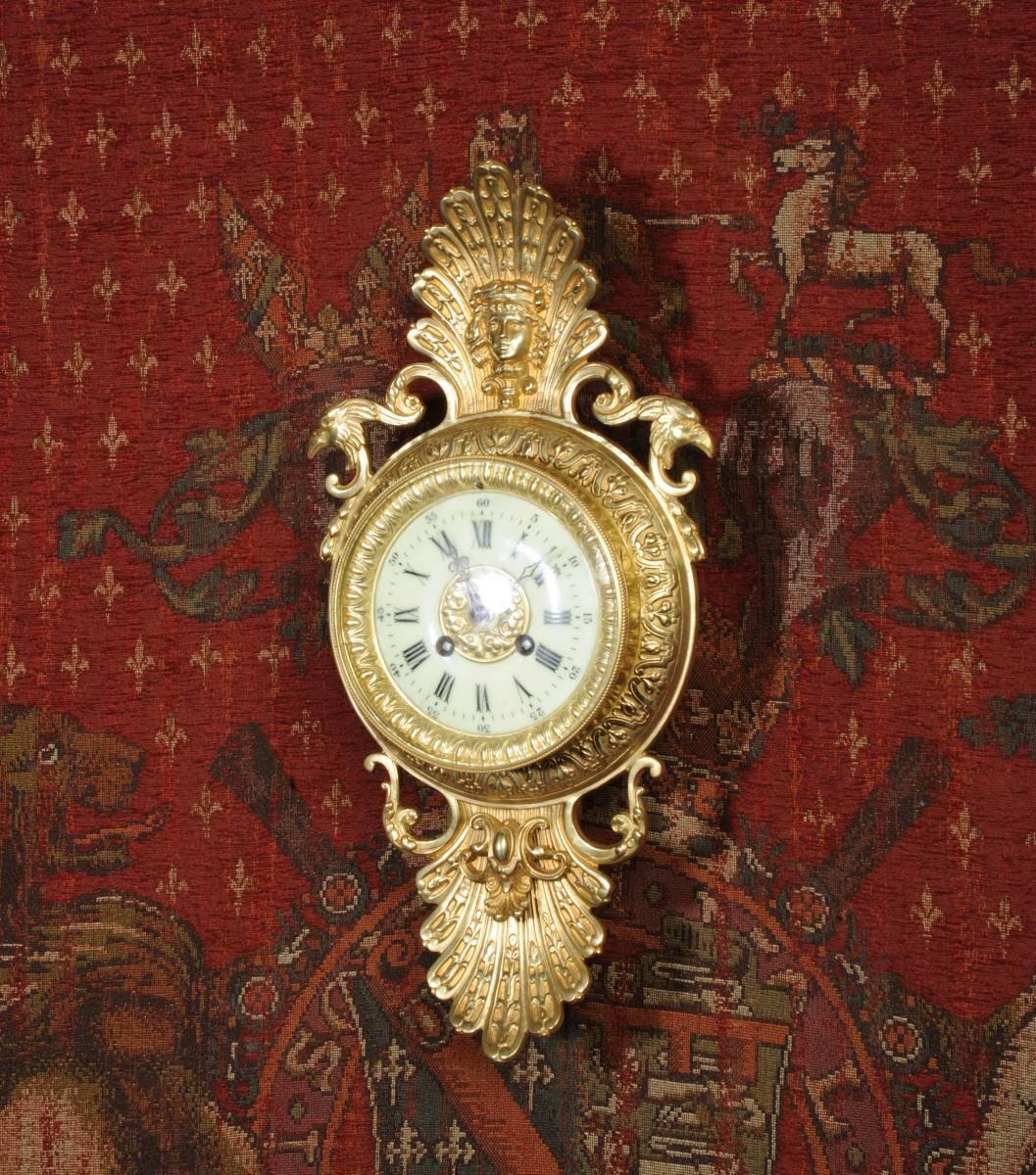 A lovely, small sized, original antique French wall clock. It is classical in style, modelled in gilded brass and features eagles heads to the shoulders. The superb dial is enamel on copper with a gilt brass centre and blued steel hands. It has a