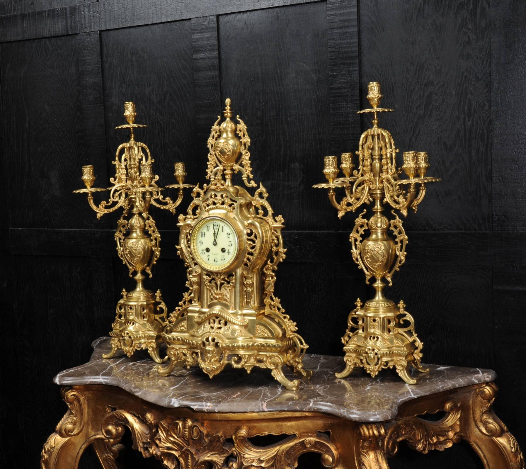 A very large gilt bronze clock set, circa 1880, beautifully and elaborately modelled in the Baroque style. It is profusely decorated with flowing foliage with a large urn with a coat of arms and a fretted front to allow the polished pendulum to be