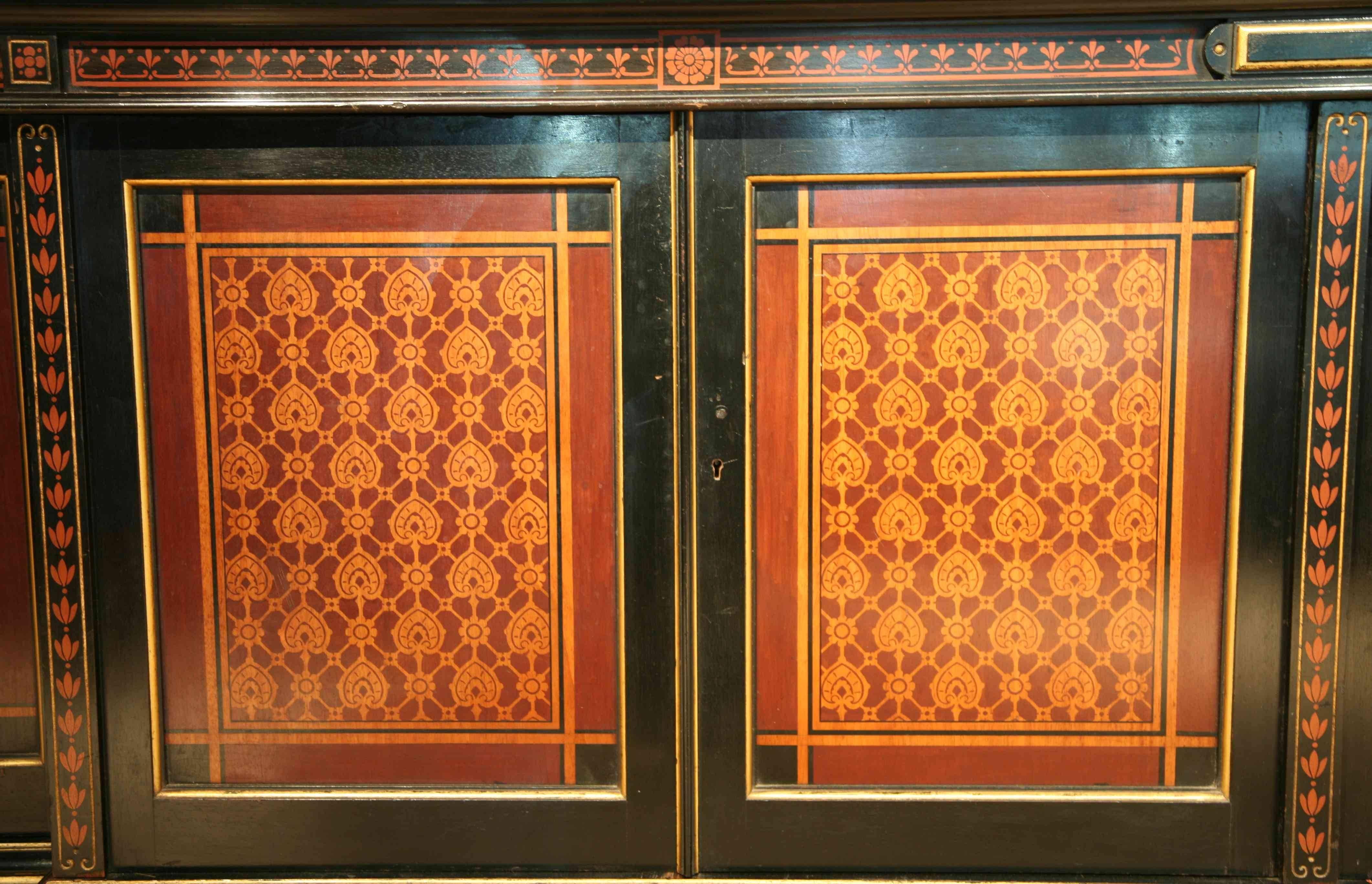 An imposing Arts and Crafts breakfront bookcase ebonized finish with stenciled polychrome decoration and gilt highlights.
Provenance: This bookcase was made for Uphill Castle, Somerset 1878. Attributed to Gillows of Lancaster.