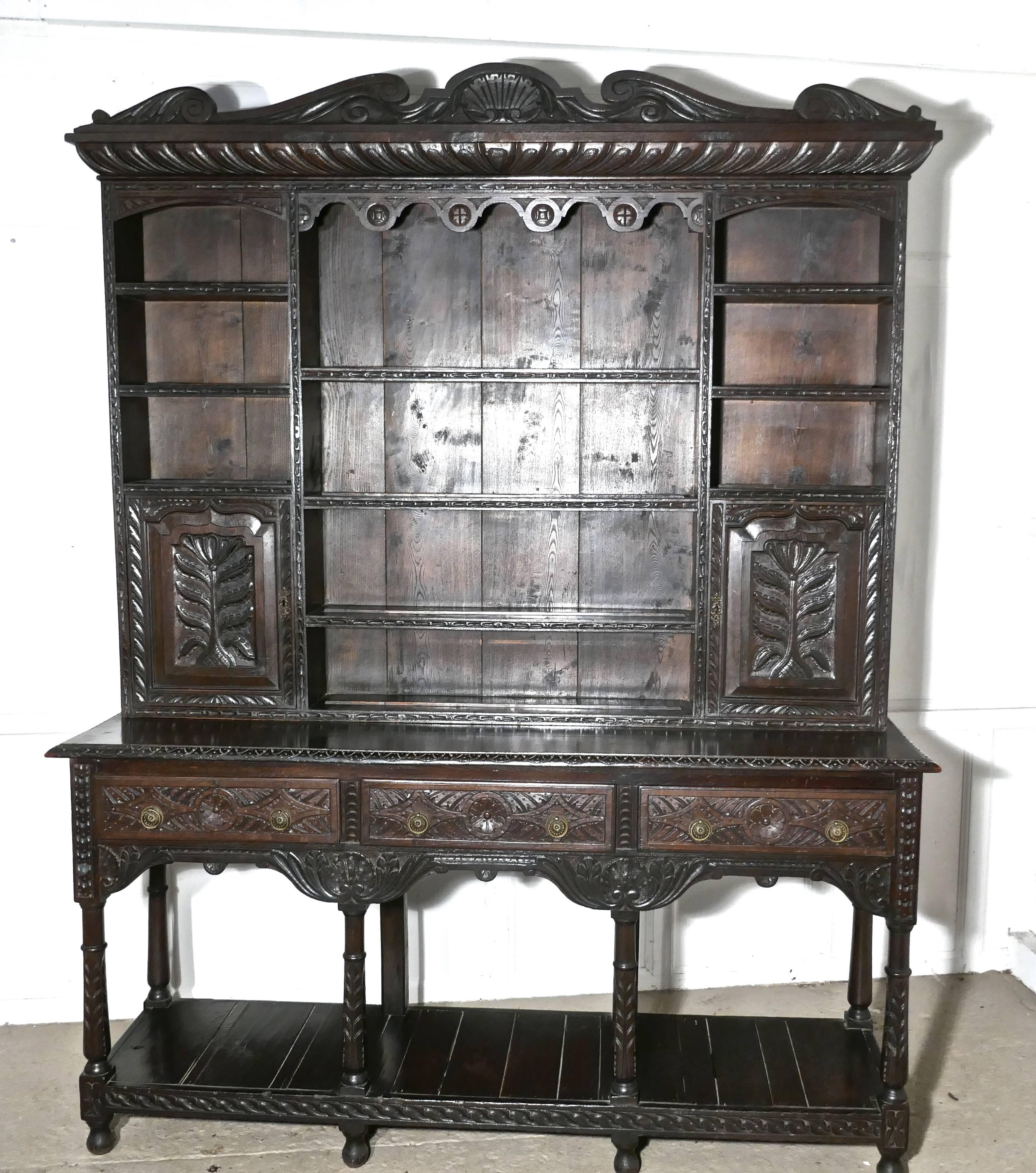 This is a superb and unusually large piece of Period Oak Furniture, the top section has central long shelves bordered by smaller shelves and small lockable cupboards
The shelves all have a carved edge and a plate rail and each of the doors of the