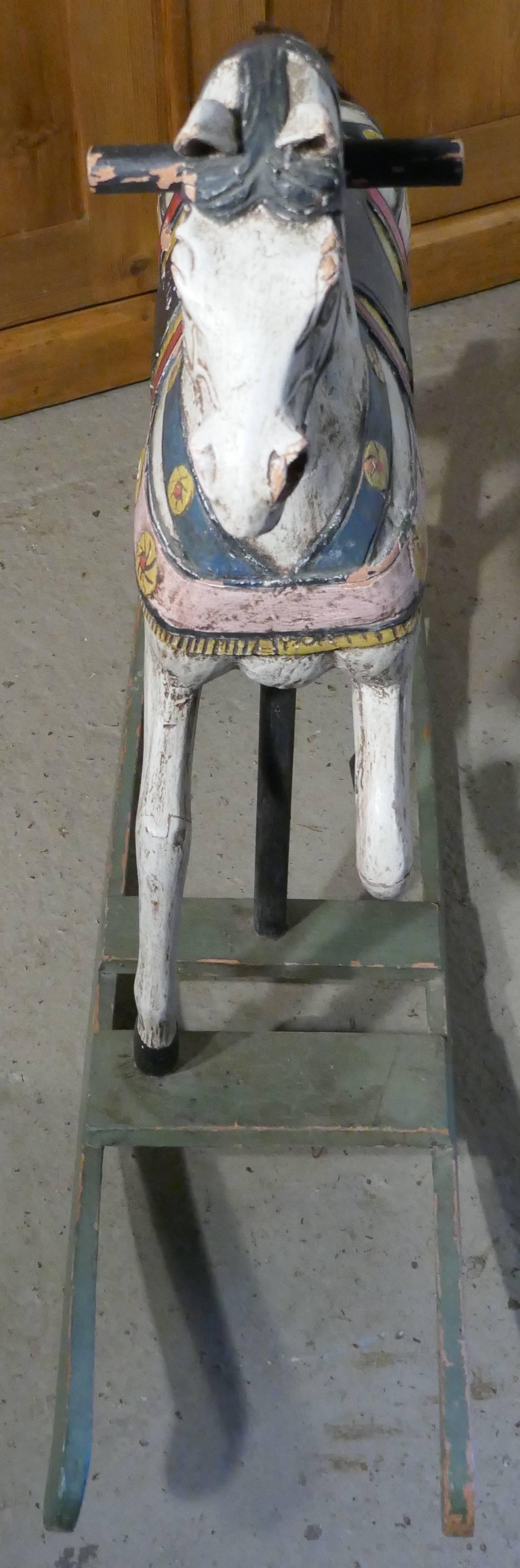 19th century carved and painted wooden rocking horse

This is a superb piece of Folk Art, it is handmade and superbly carved in wood and he stands on green wooden rockers. 
The paint is beginning to look a bit shabby but is still quite bright,