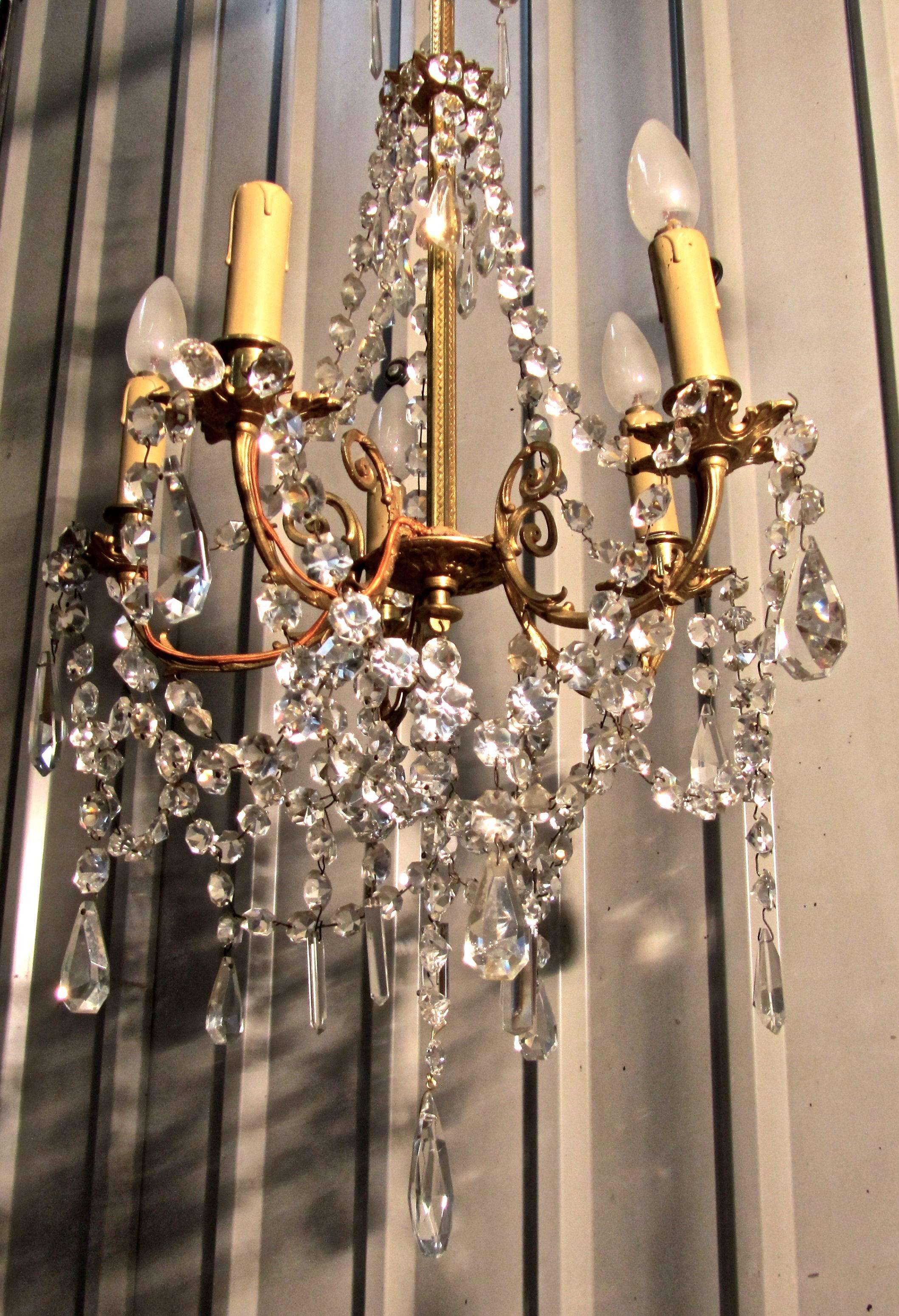 A charming and large French cut glass and brass five branch chandelier.

This is an excellent quality piece, the decorated brass centre column supports the scrolling branches, the five arms are hung with many strings of beads and flat cut glass