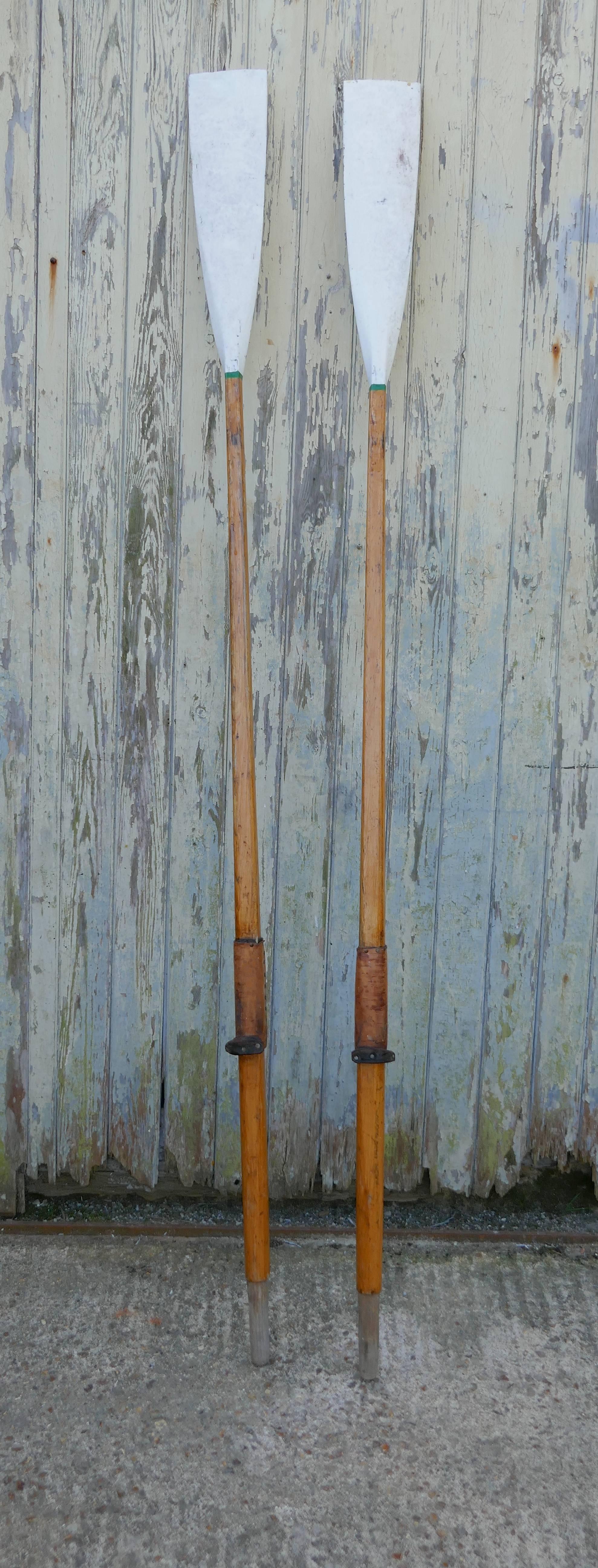 A pair of decorative long sculling oars

This is a fine quality pair of long oars from a Thames Rowing Club, the spoons or blades are painted in white and the long ash shafts are in their original varnished finish each with their old brown leather