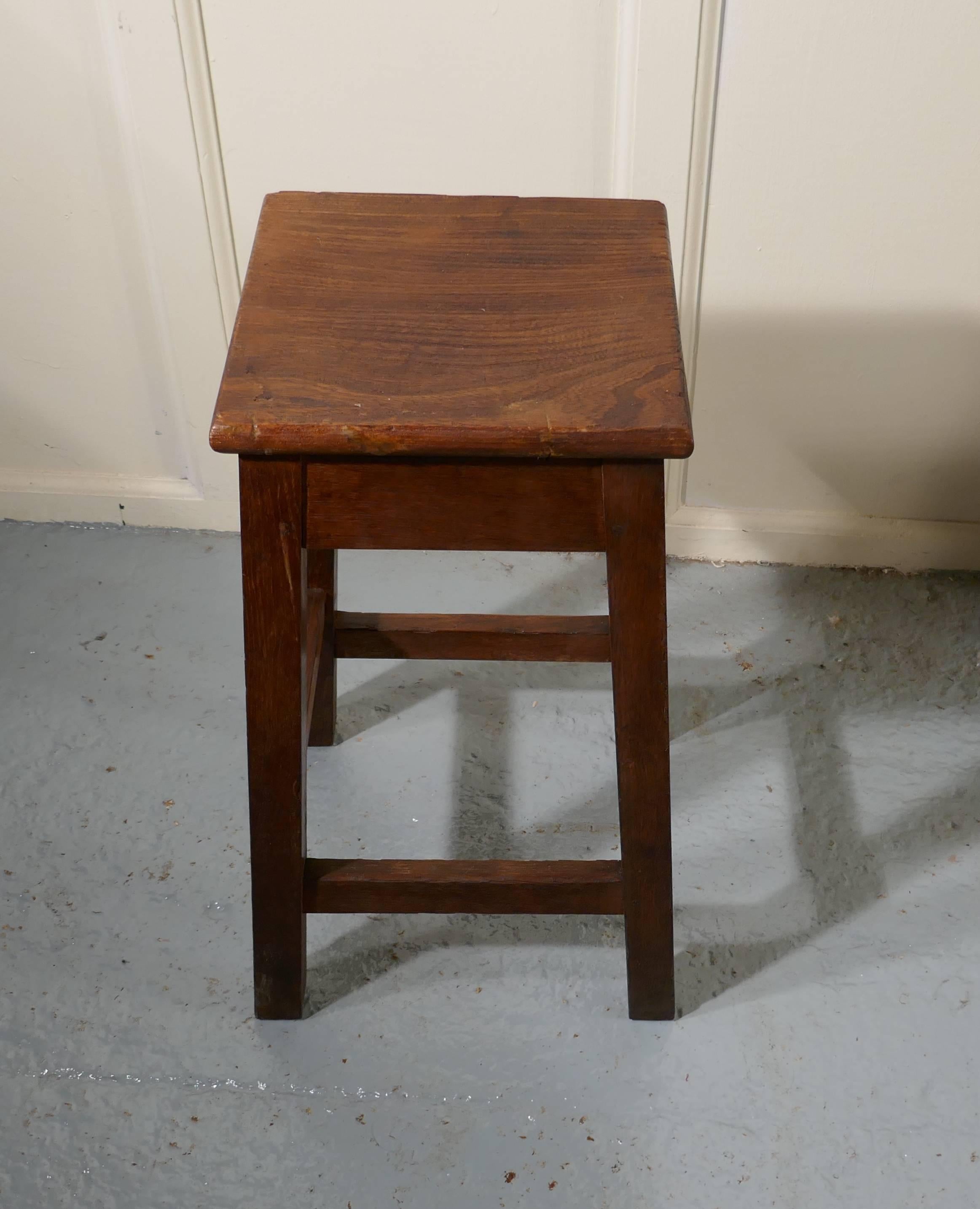Farmhouse kitchen oak stool

This is a good chunky piece, it is originally from a Chemistry Lab (well thats what is written in ink underneath), it has an 1” thick oak seat and square oak legs 
The stool is in good sound condition
 The stool is