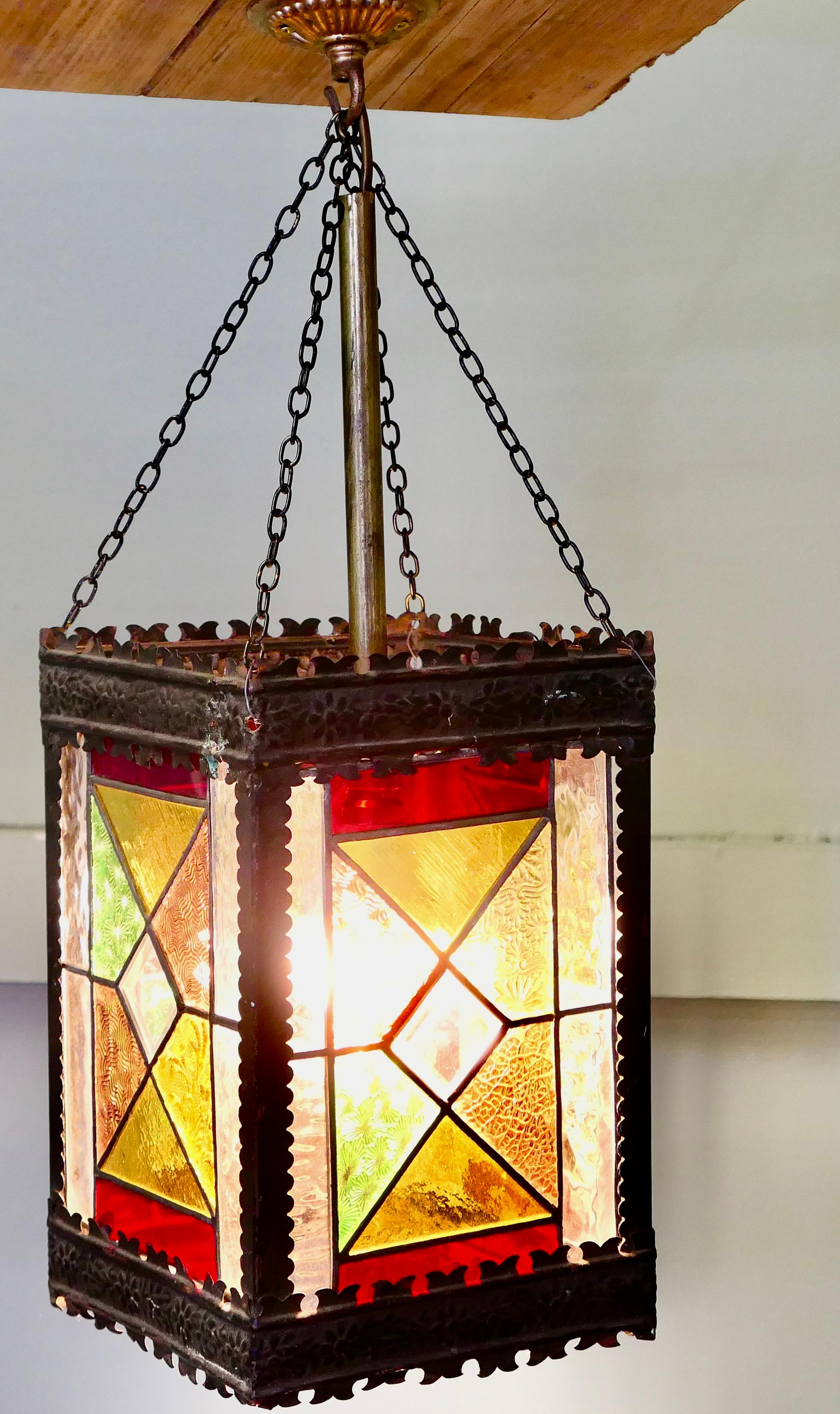 Arts and Crafts Stained Glass Hall Lantern (Lanterne de salle en verre teinté)

Cette lanterne, de conception classique Arts and Crafts, est dotée de panneaux de verre coloré au plomb placés sur chacun des quatre côtés du cadre métallique. Il s'agit