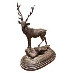 Sculpture en bronze signée représentant un cerf debout sur un rocher, posée sur un socle en marbre