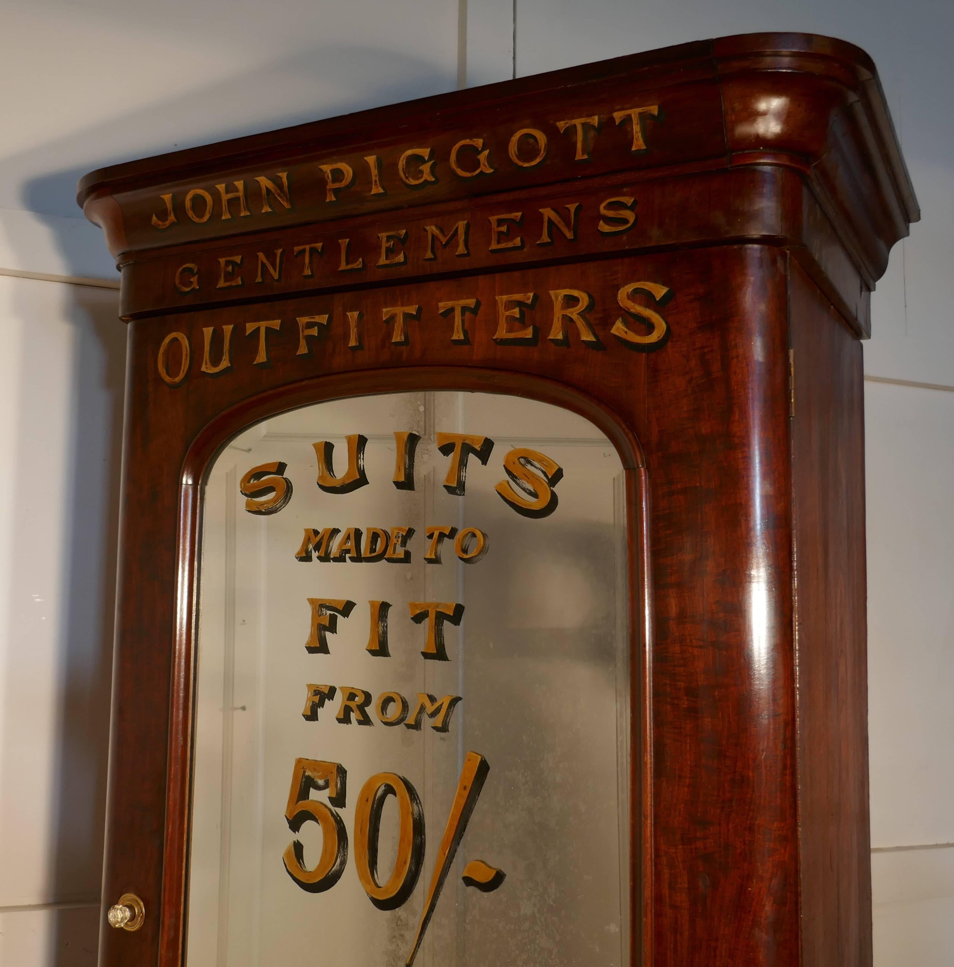 This is a very unusual piece, a Victorian mahogany press which has gold and shadowed lettering painted both on the mahogany and on the mercury glass mirrored door.
The wardrobe has been painted for “John Piggott, Gentleman’s Outfitters” it is a