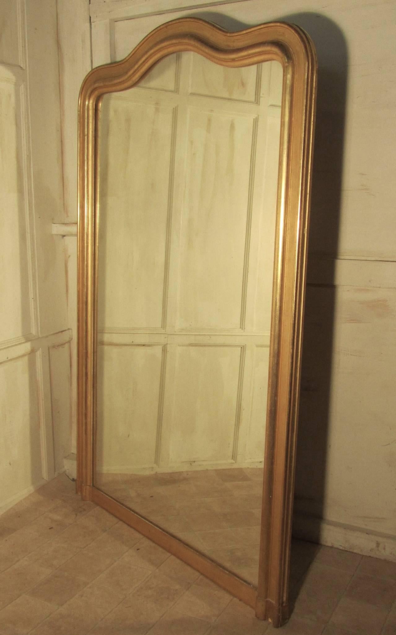 This is a very large statement piece and genuine 19th century French chic furnishing, the 4” frame which has a serpentine arch at the top has a charming slightly faded pale gold finish, it is sound and very heavy, the looking glass is original and