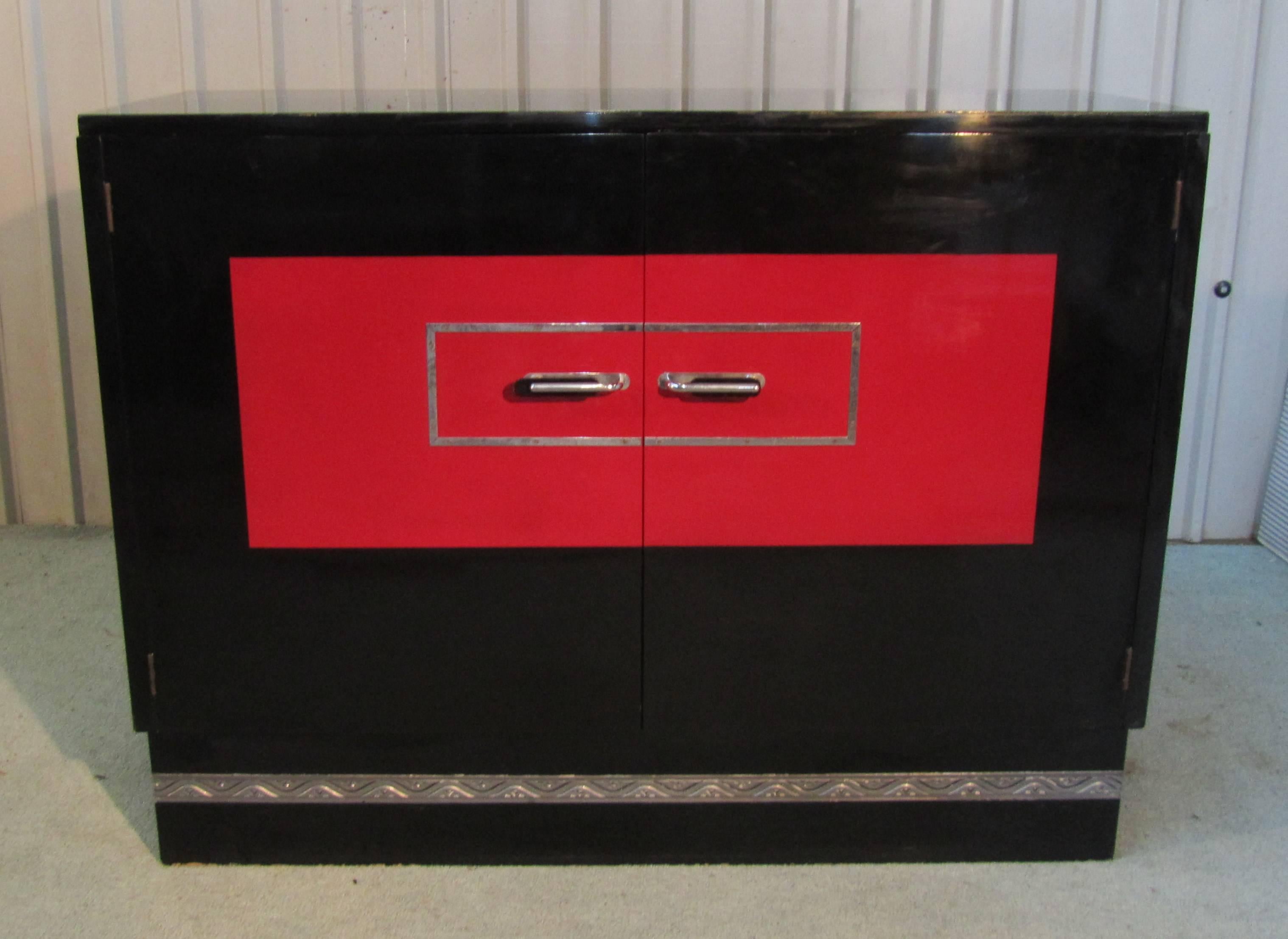 A superb and extremely rare piece, the sideboard is finished in high Gloss Lacquer, all in Black apart from the scarlet panel on the front, this has a chrome decoration and chrome and Bakelite handles 

The Classic design of this piece is
