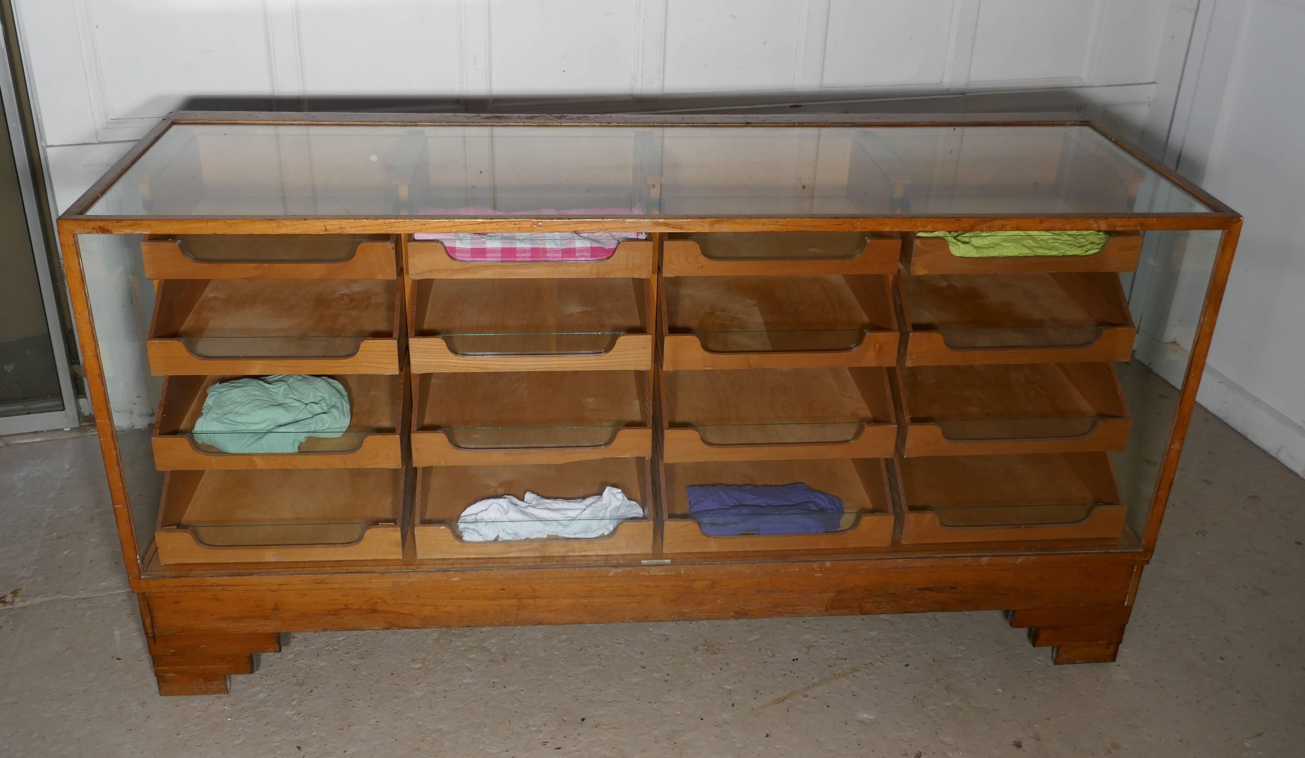 This haberdashery shop counter is a good large size, it has 4 banks each of 4 graduated drawers with moulded wooden handles, the fronts of the drawers have a glass insert to give good viewing of the contents. 
The cabinet is made in golden Oak,