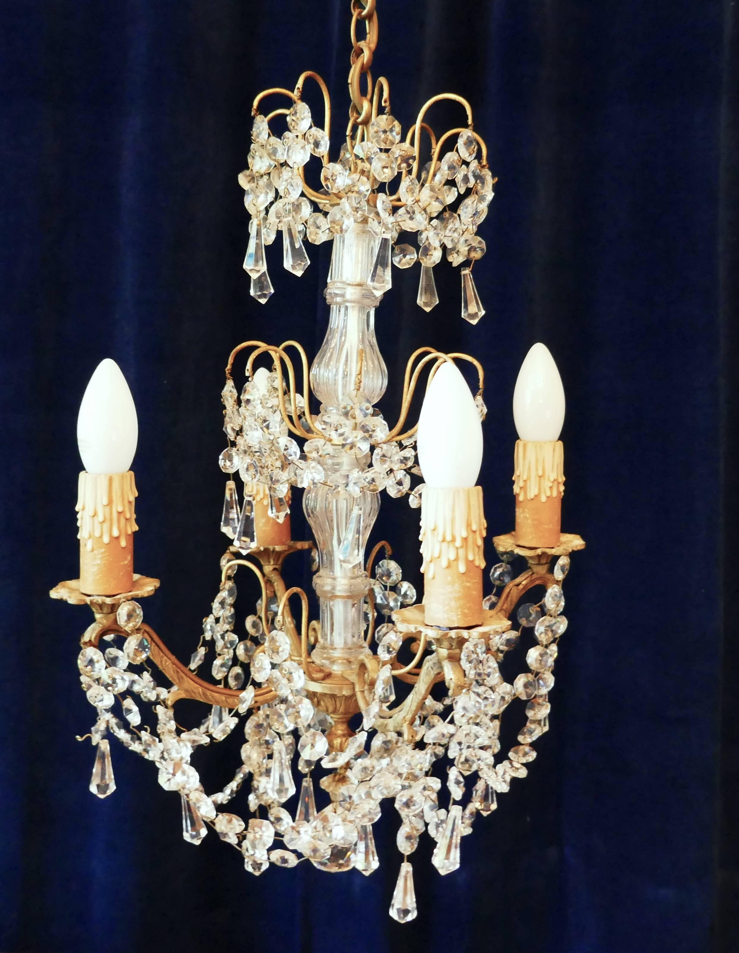 This is a stunning piece, it is a “Cristal de Bohême” four branch chandelier made by Lucien Gau, Paris

This is an excellent quality piece, it has a glass baluster column in the centre, four brass scrolling branches supporting brass sconces and