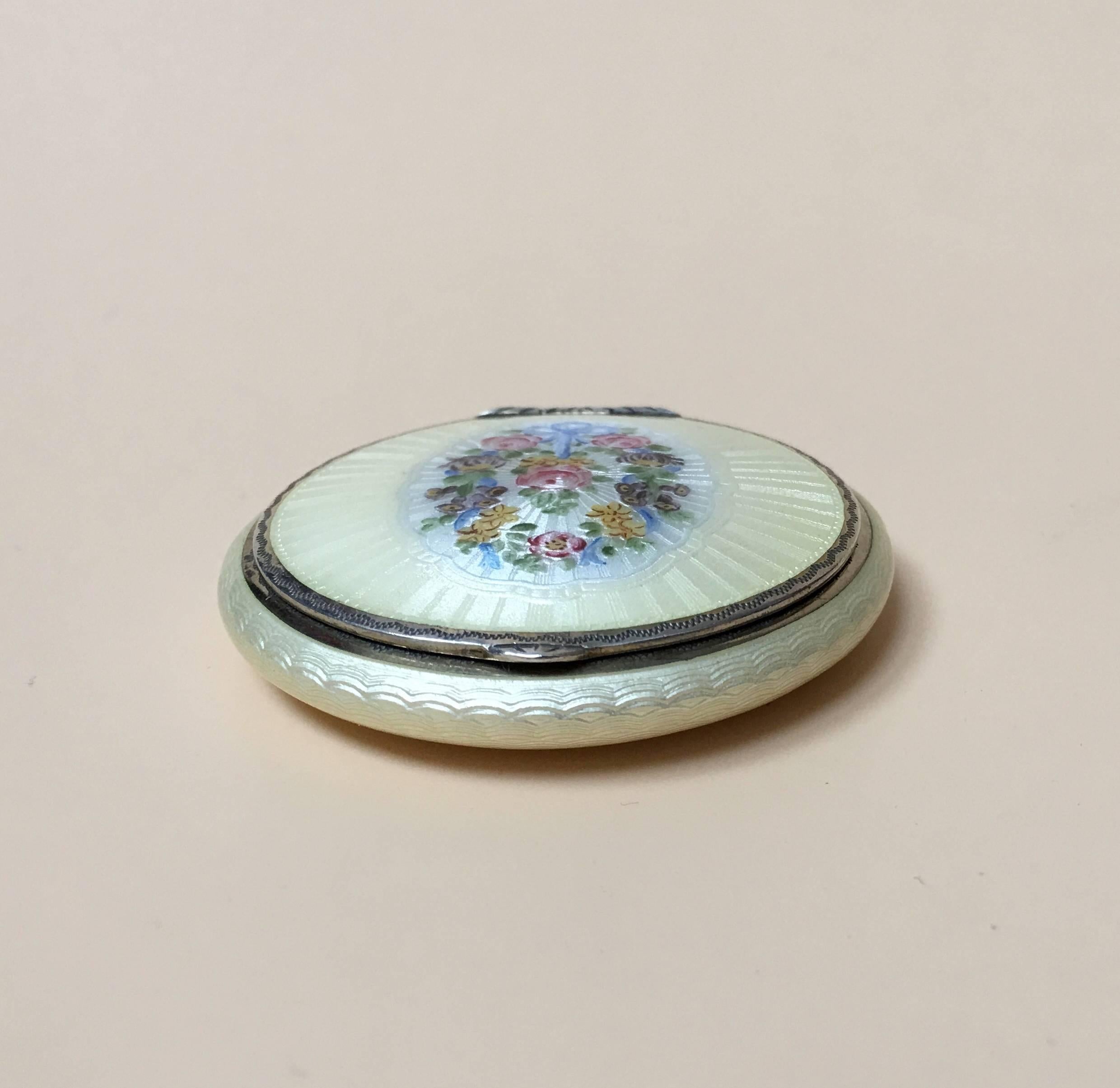 This beautiful Compact has a Primrose Ivory background and is decorated with a garland of flowers tied with a blue ribbons
The Enamel is of such fine quality the central decoration looks though it has been embroidered, it has a beautiful design