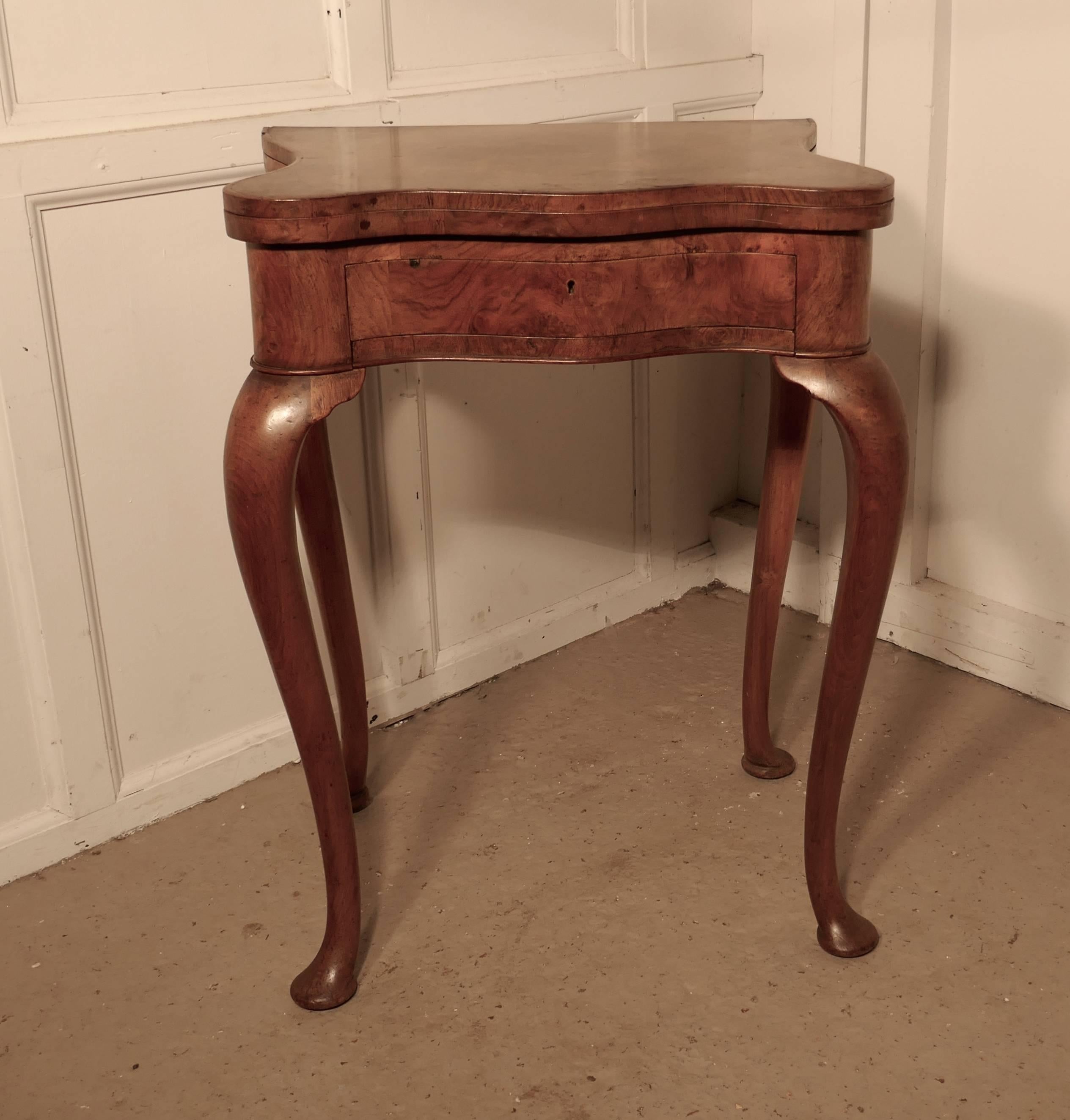 This is a charming piece, the table has an unusual scalloped shape, it stands on slender cabriole legs and has a drawer with a side beneath for holding game boards
The top is made in superbly matched burr walnut veneers, the tabletop folds out
