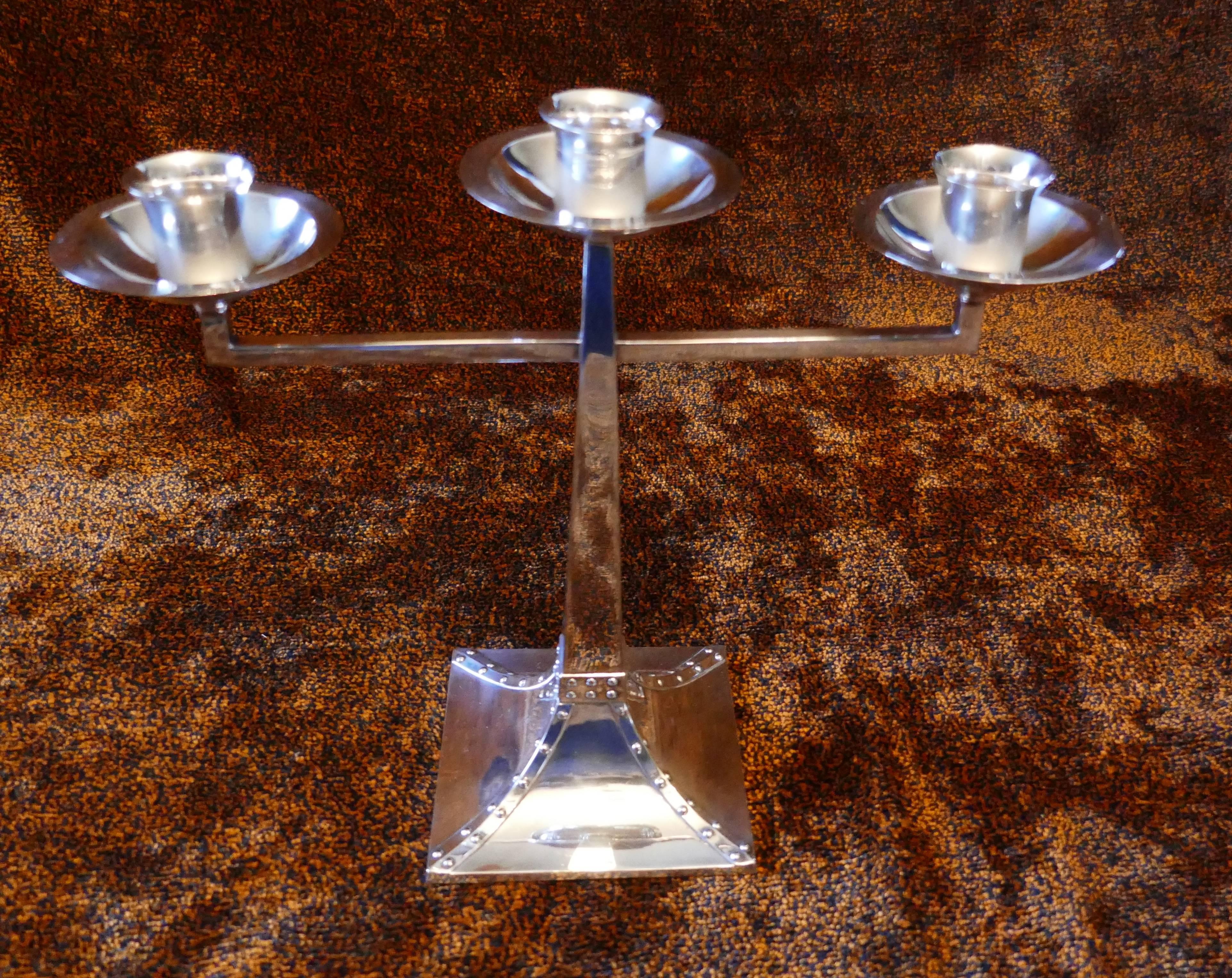 A pair of James Dixon & Sons three-branch silver Arts & Crafts candelabra

This is a magnificent pair of early 20th century table candelabra, each one has three sconce topped branches set on a tapering rectangular stem. The base of the candelabra