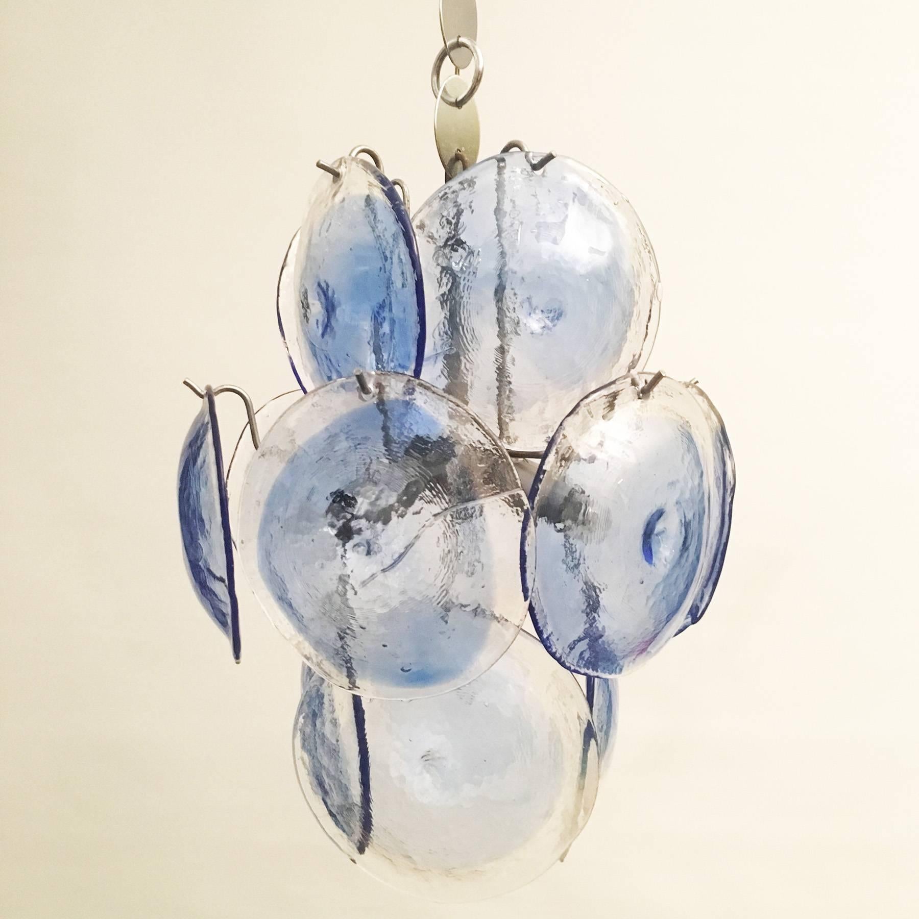 Beautiful small chandelier, designed in the 1970s by Gino Vistosi, manufactured by Vistosi Murano.
The chandelier is made of a nickel and chrome-plated metal fixture and 14 handblown glass disks in clear and blue. It is equipped with four E14 lamp