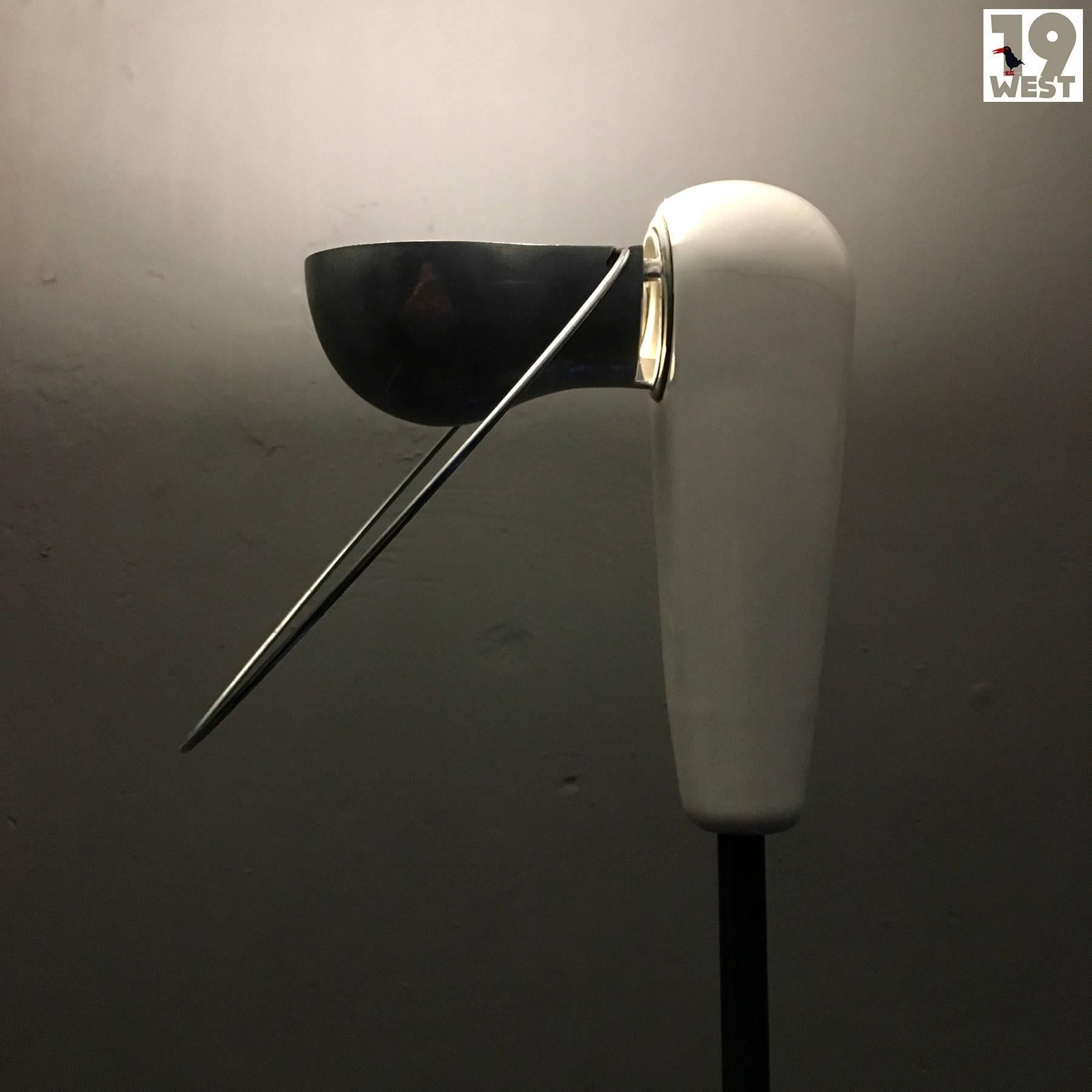 Bi-Bip floor lamp, designed in 1976 by Achille Castiglioni, manufactured in Italy by Flos. The piece stands out for its reduced design and beautiful materials. Base and head are made of white porcelain, the reflector of polished aluminium. It can be