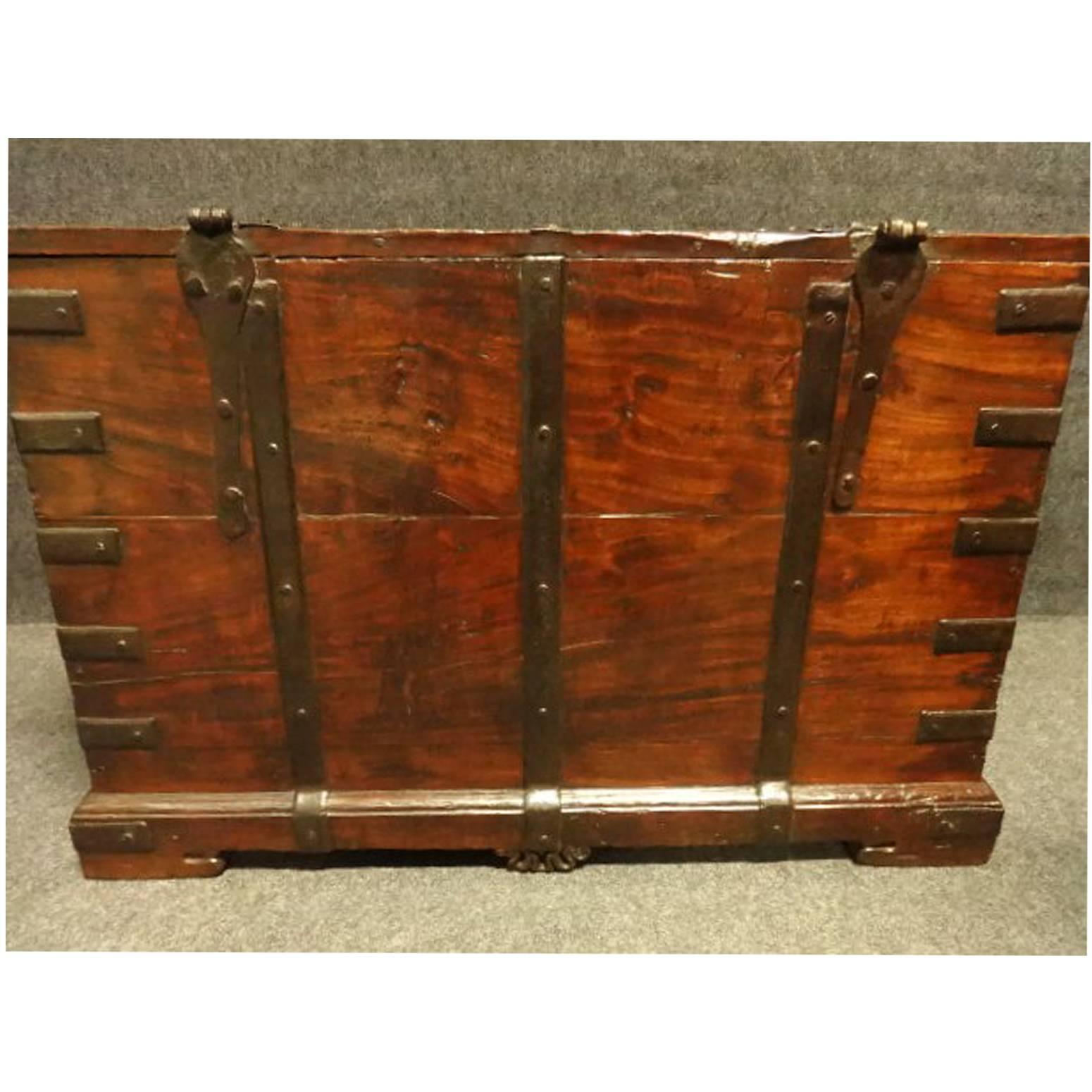 A very good teak box, bound with iron straps and brass studs, iron hasp, candle box to the inside with a secret compartment, excellent color and condition.