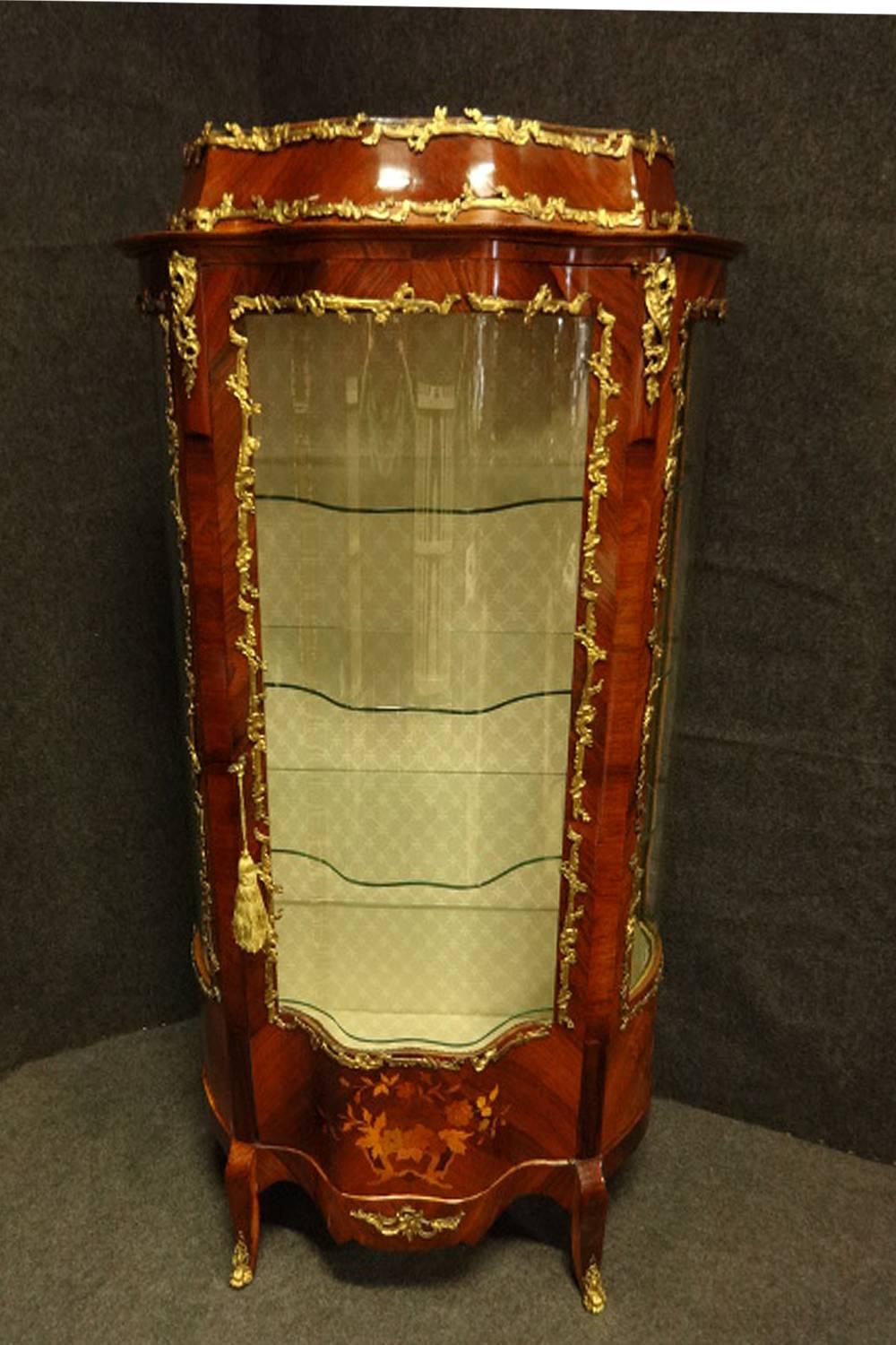 A very good double serpentine fronted kingwood vitreen with floral marquetry panels to the base, bowed glass sides, four shaped plate glass shelves, gilt metal mounts, relined and repolished to a very high standard.
 