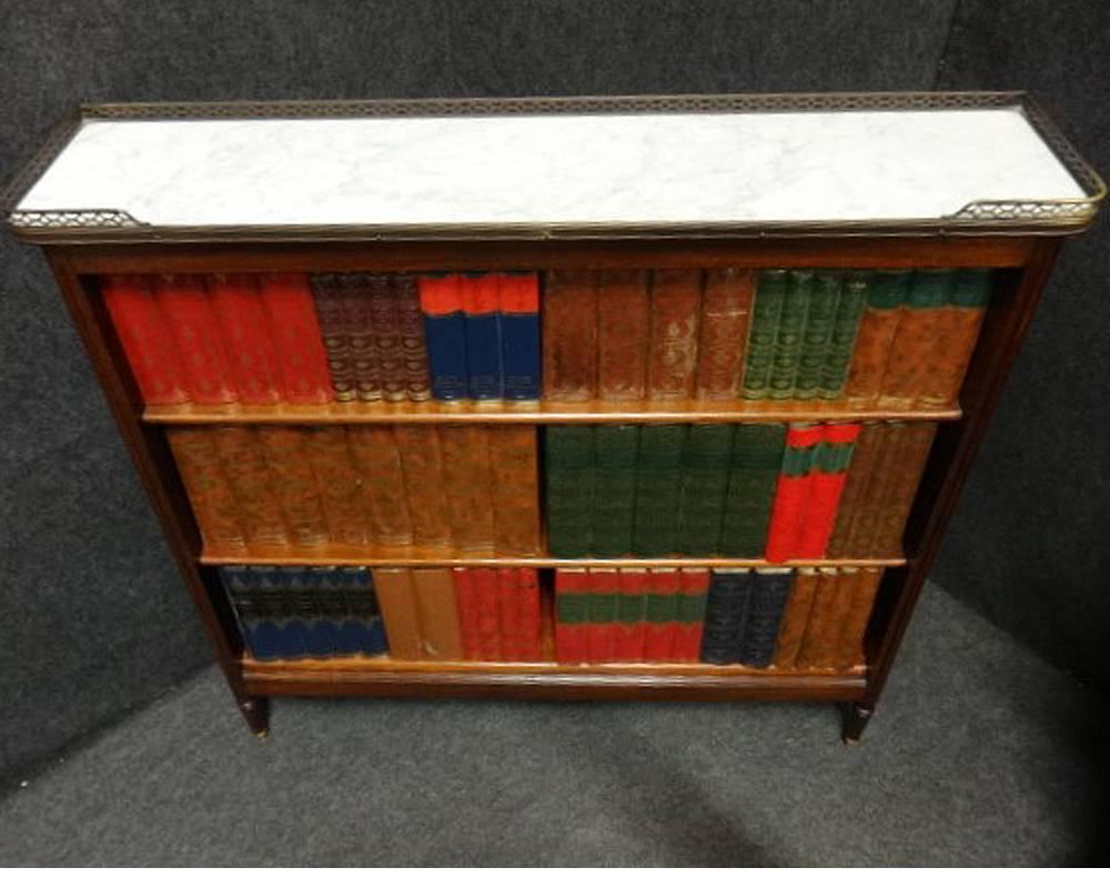 A very good French open bookcase, two adjustable shelves, brass beading to the sides, brass feet, brass fretted gallery and marble top, in excellent original condition.