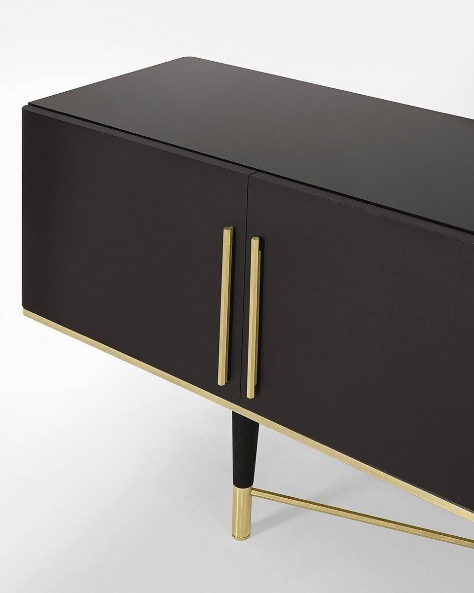 Sideboard in black lacquered ash. Satin brass and satin brass lacquered aluminium details. 6mm bright liquorice painted tempered glass top and inside back. Rhomboidal engraved pattern on the inside glass back. Supplied with smoked “grigioItalia”