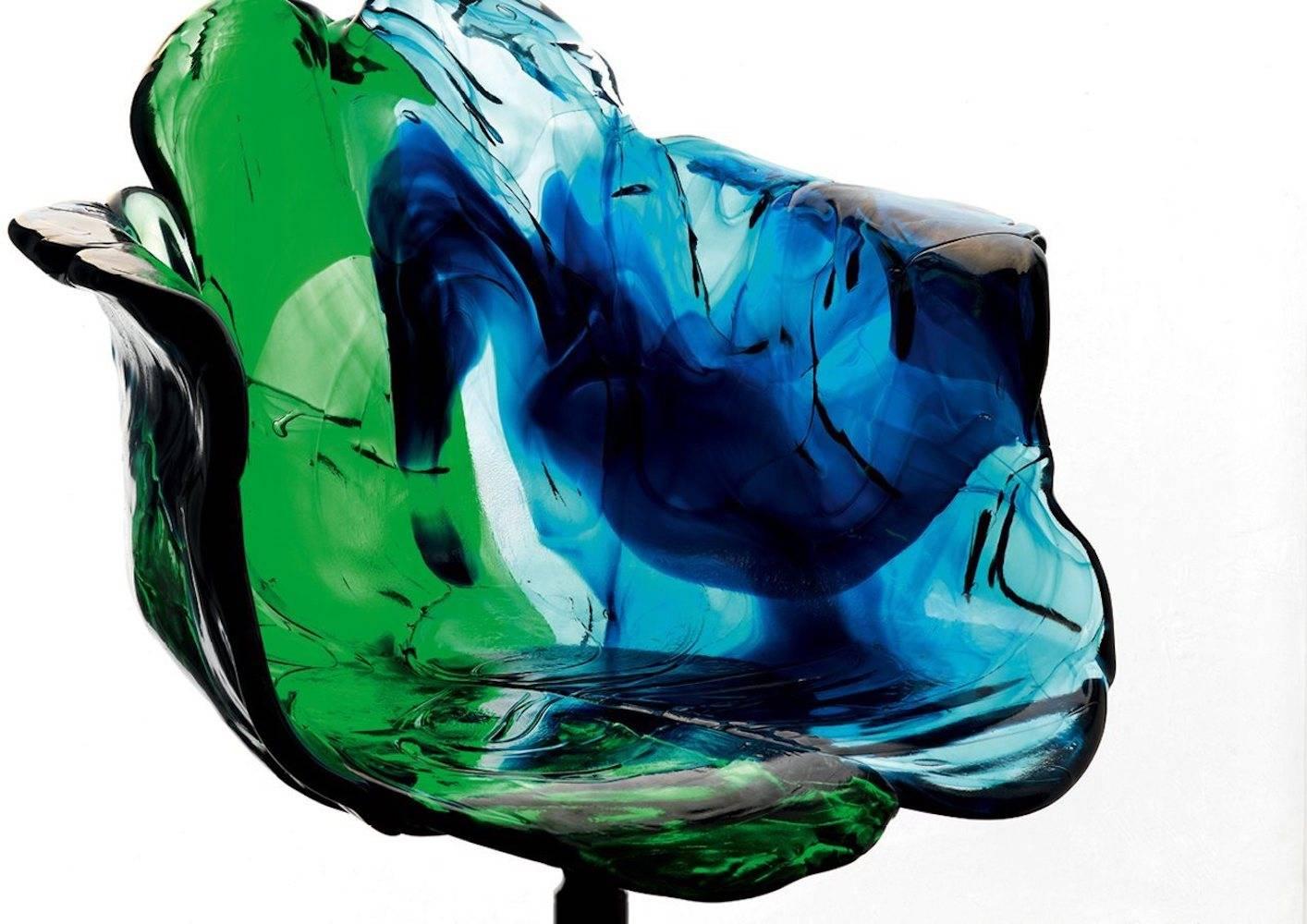 Armchair with armrests in polycarbonate, entirely handmade. The petals, in transparent and soft colors, mix green and blue. Wonderful play of colors modelled by hand in a transparent material. It is supported by a semi-gloss black pedestal, which