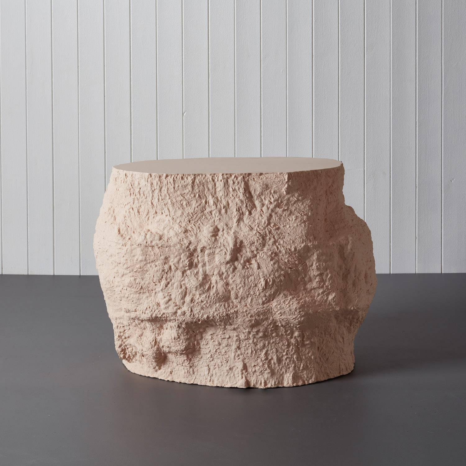 “Acacia side table” by Malgorzata Bany, a light pink jesmonite side table with a smoothened top and richly textured body. The piece takes inspiration from daily cleansing rituals and the process of decay, in particular Japanese Tsukubai- ceremonial