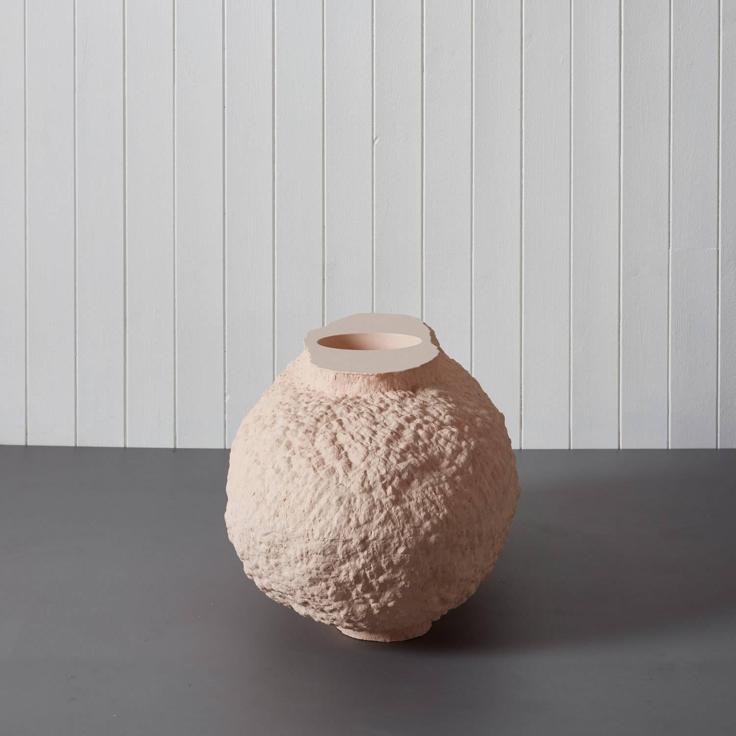 “Acacia Vessel” by Malgorzata Bany, a large light pink jesmonite vessel with a smoothened top and richly textured body. The piece takes inspiration from daily cleansing rituals and the process of decay, in particular Japanese Tsukubai- ceremonial